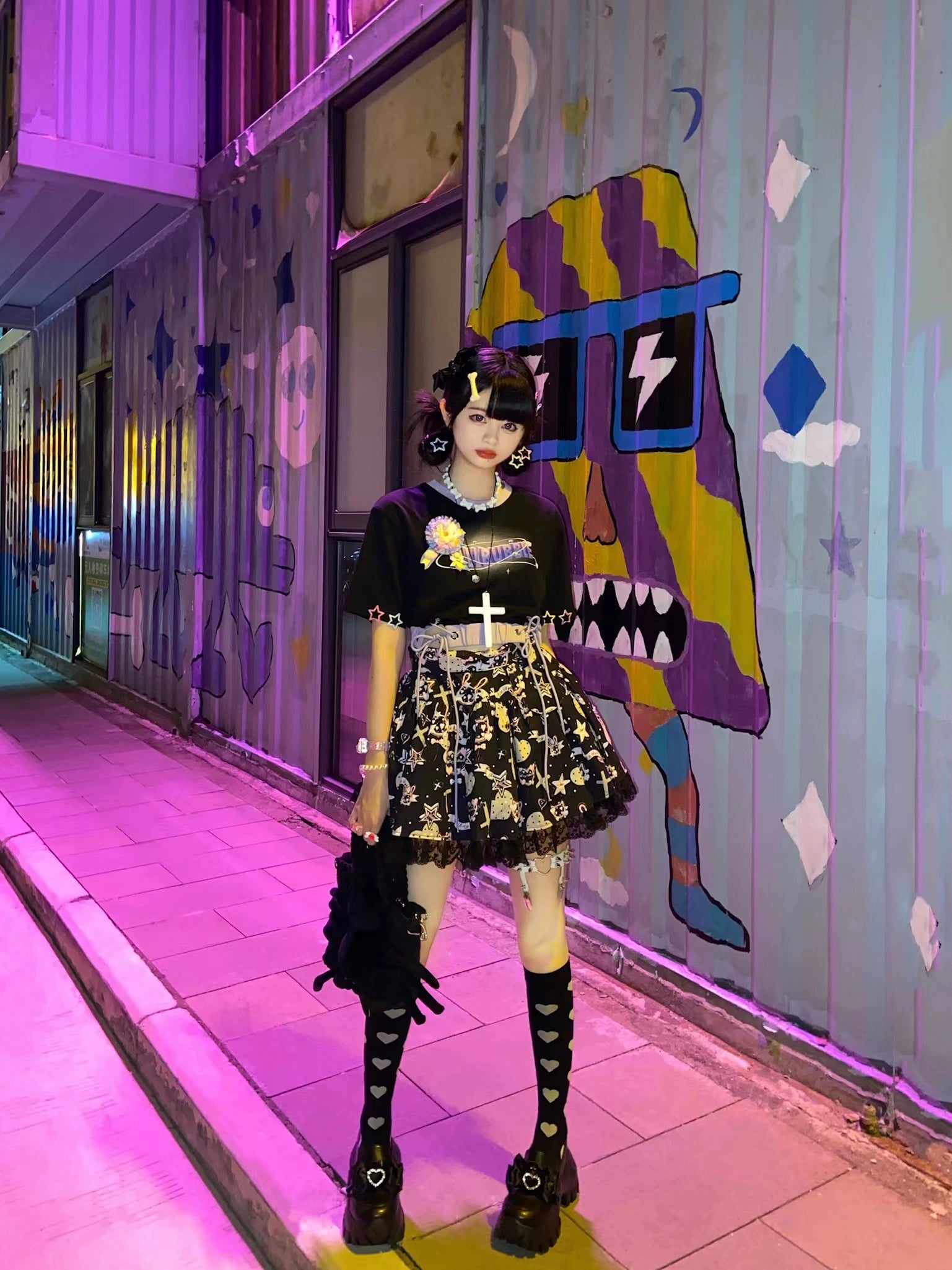 Black JK platform shoes styled outdoors at night with neon graffiti alley backdrop, worn with printed skirt and lace stockings