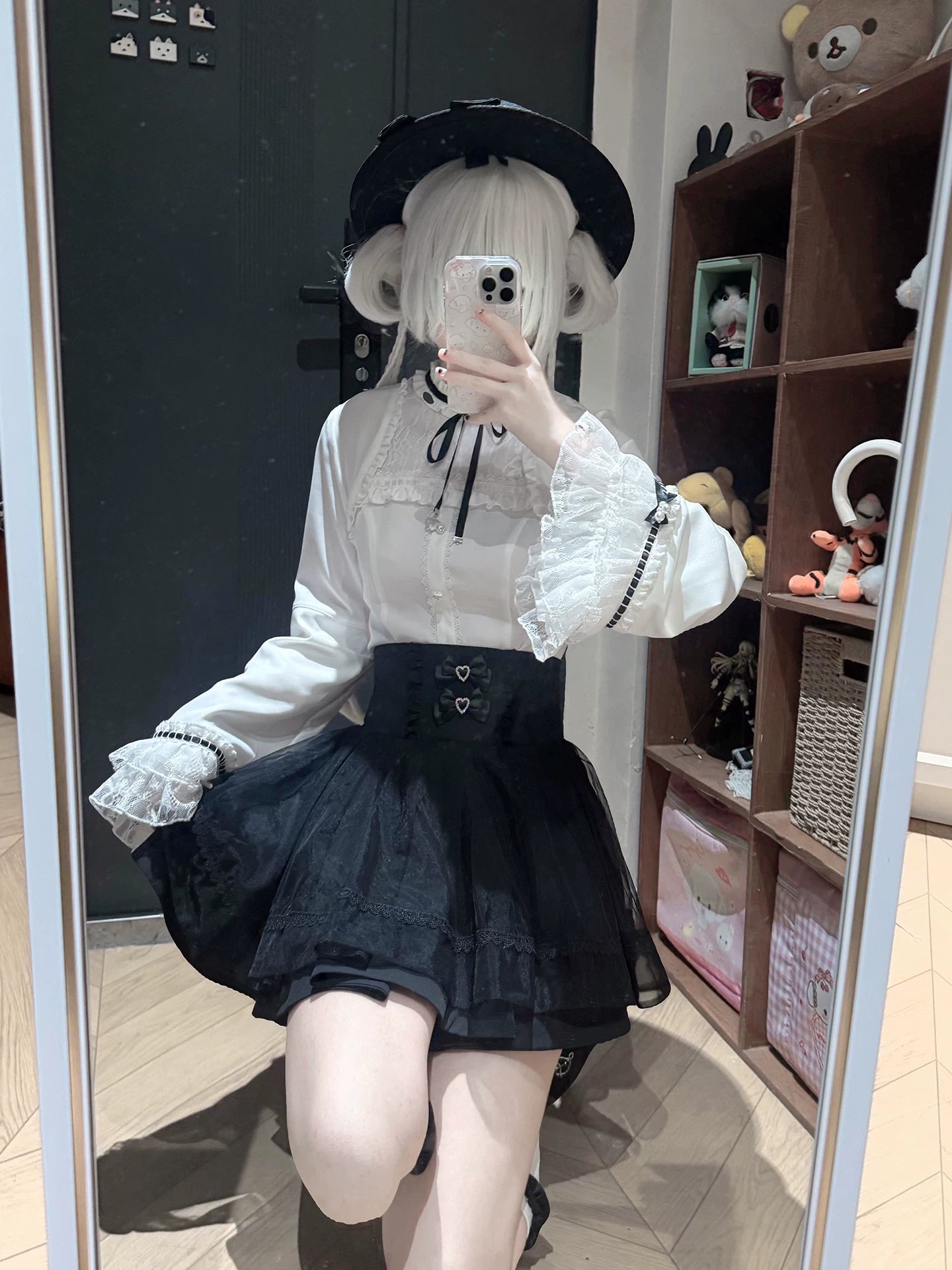 Side view of jirai kei two-piece outfit featuring ruffled lace blouse with black neck ribbon and high-waisted a-line tulle skirt, model wearing black bowler hat