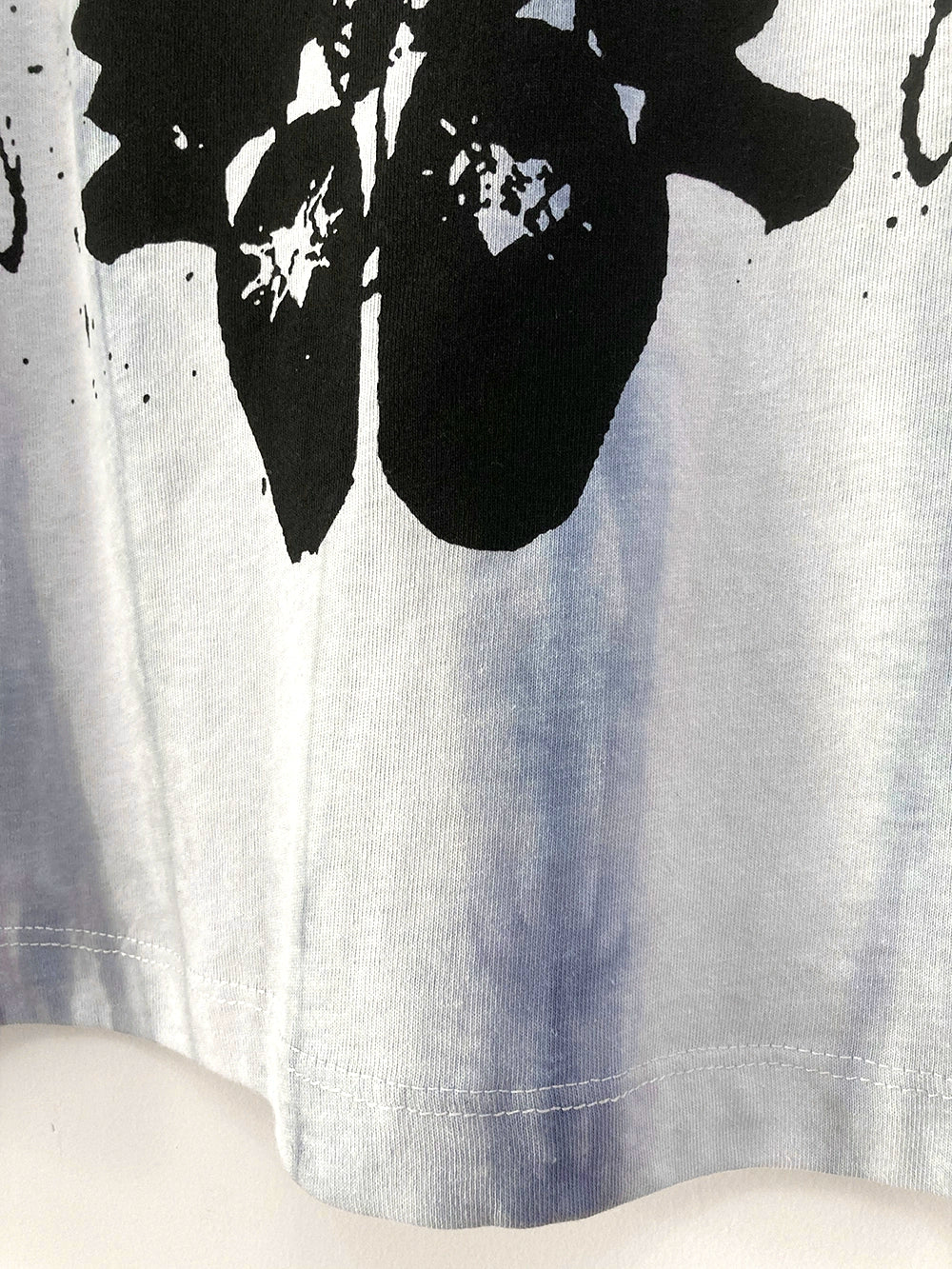 Hem and bottom section detail of oversized tie-dye gothic jirai kei angel wings t-shirt showing fabric quality and print reach