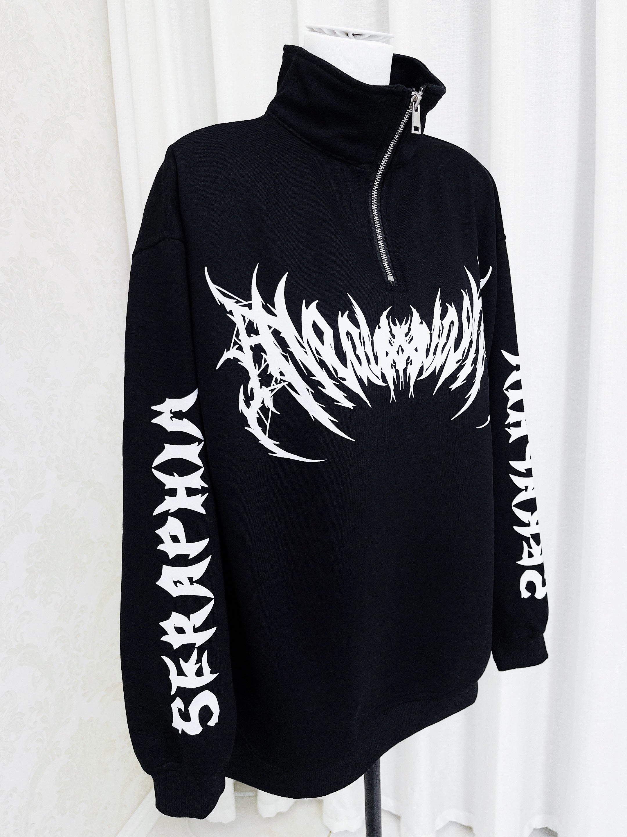 Jirai Kei gothic black and white half-zip sweatshirt front view on display mannequin, showing bold graphic print and oversized silhouette with dropped shoulders