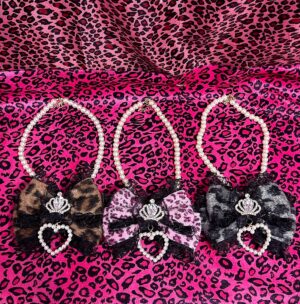 Jirai Kei leopard pearl choker necklace collection featuring three color variations with crown and heart rhinestones on pink leopard print background flat lay