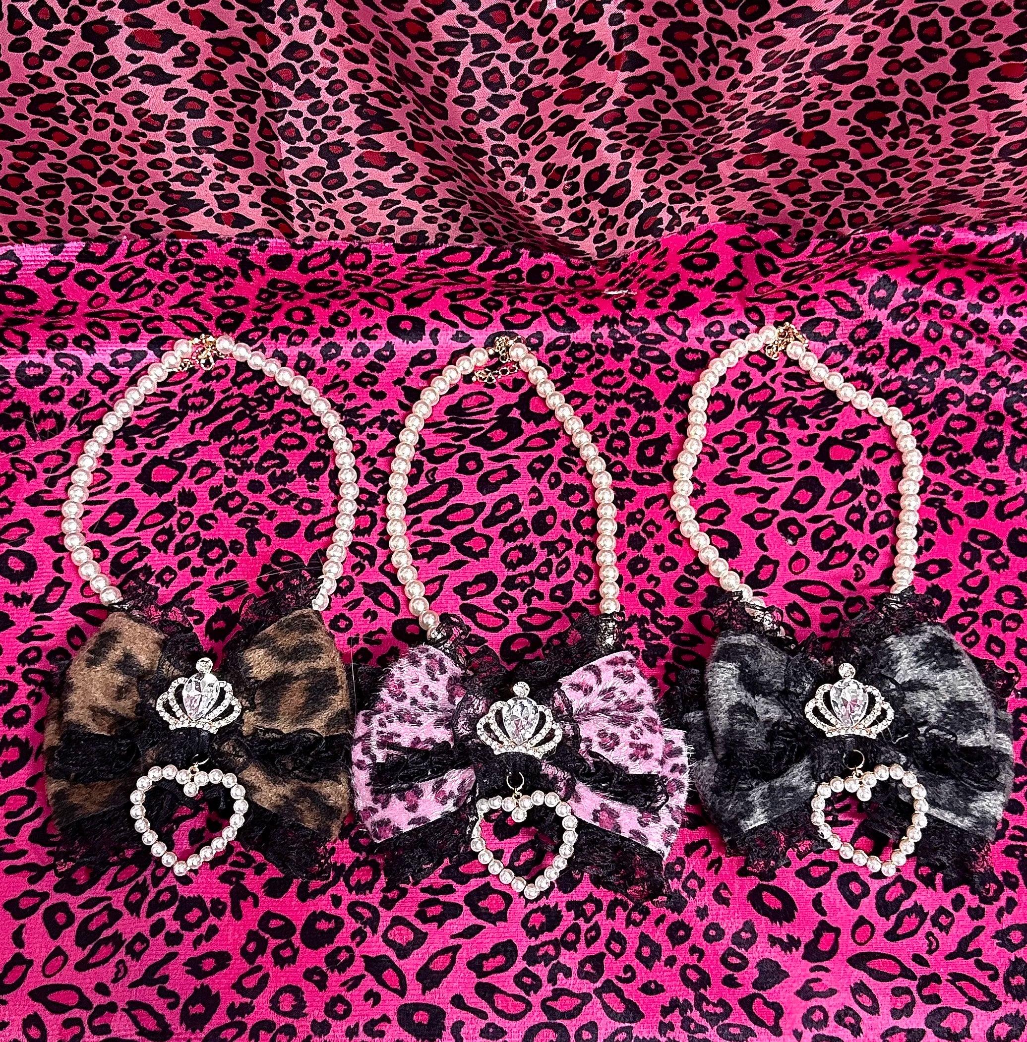 Jirai Kei leopard pearl choker necklace collection featuring three color variations with crown and heart rhinestones on pink leopard print background flat lay