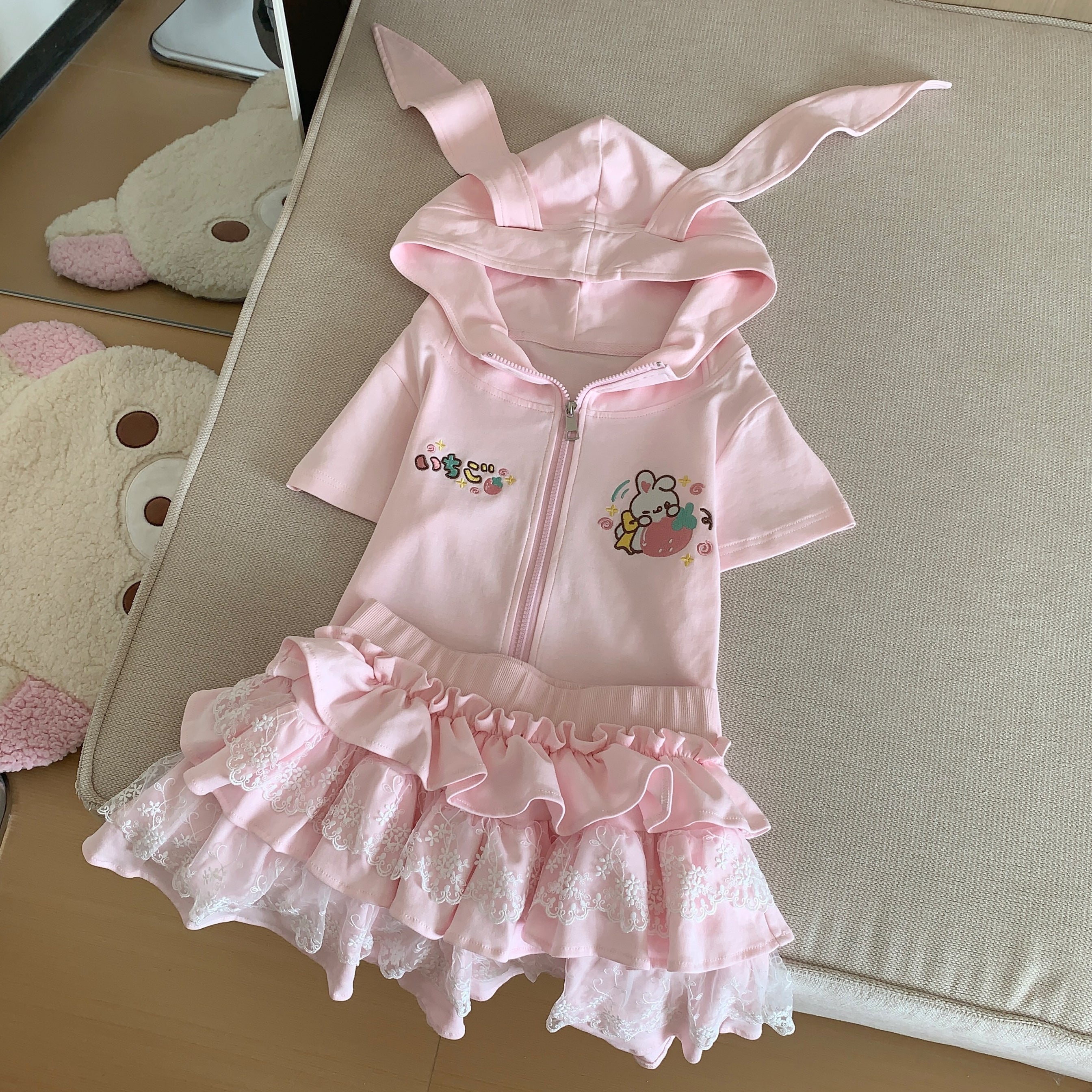 Pink short-sleeved bunny-ear hoodie jacket with matching ruffle lace skirt two-piece set flat lay presentation