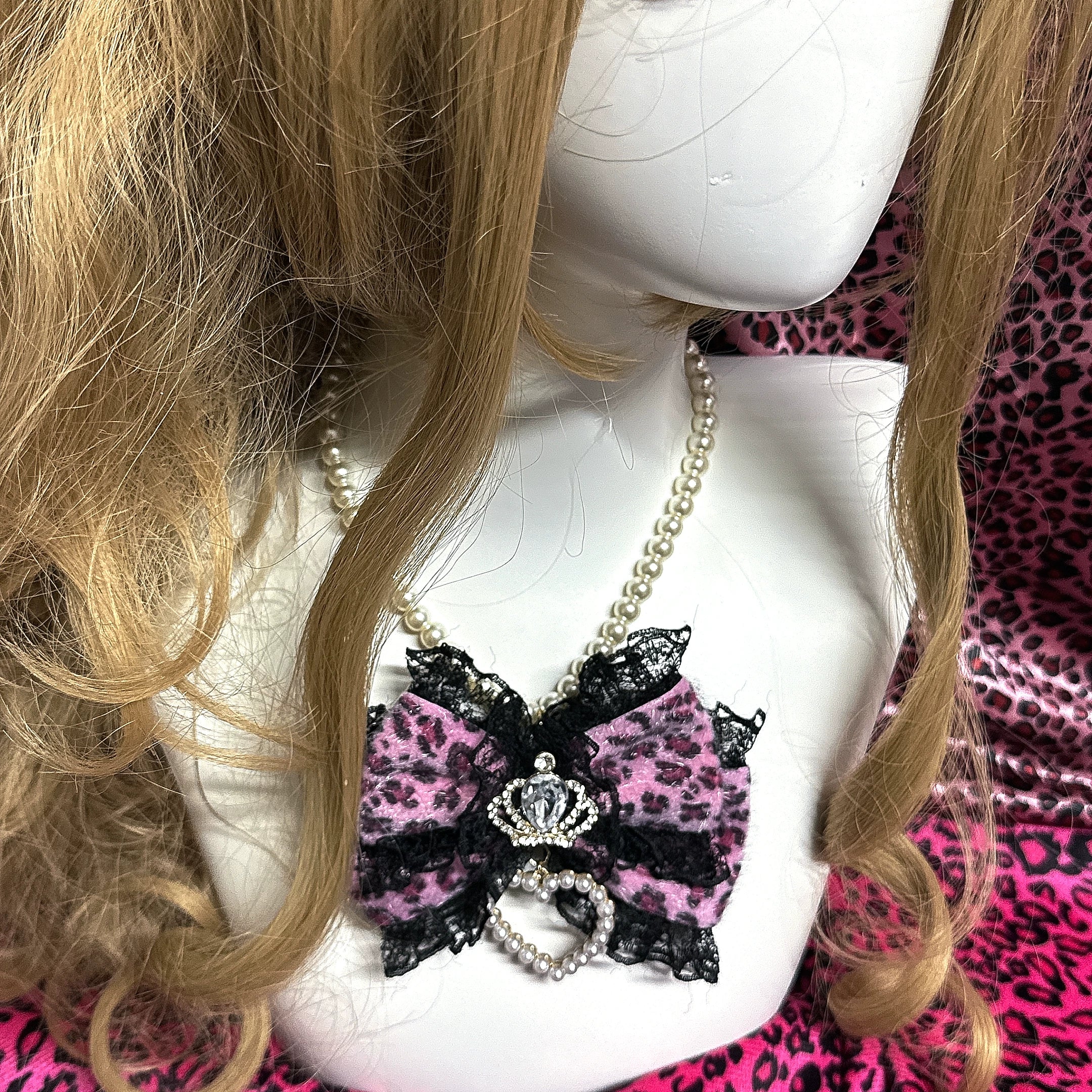 Pink leopard pearl choker necklace with crown rhinestone and pearl heart pendant on blonde wig mannequin close-up front view Jirai Kei style