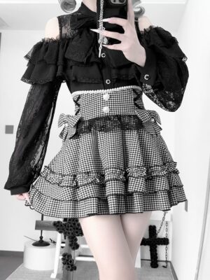 Black houndstooth jirai kei ruffle skirt with detachable bow worn with off-shoulder lace blouse, front half-body view showing layered ruffled hem and buttoned waist