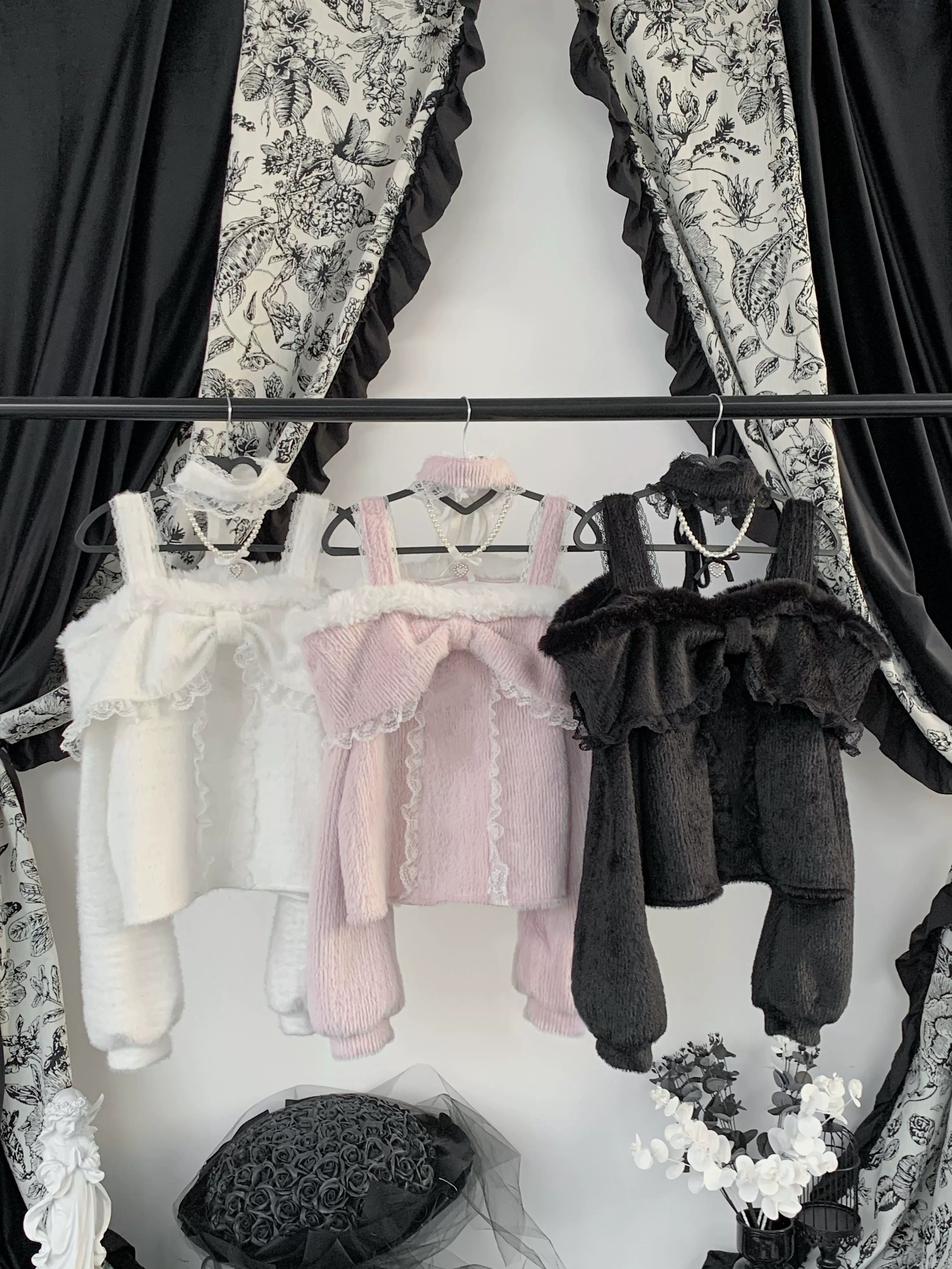 Three color variants of off-shoulder plush fleece tops displayed hanging - white, pink, and black - showing fuzzy fabric texture and construction details