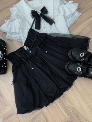 Black Jirai Kei bubble skirt with rhinestone trim and detachable bow, flat lay styling with coordinating accessories on wooden floor