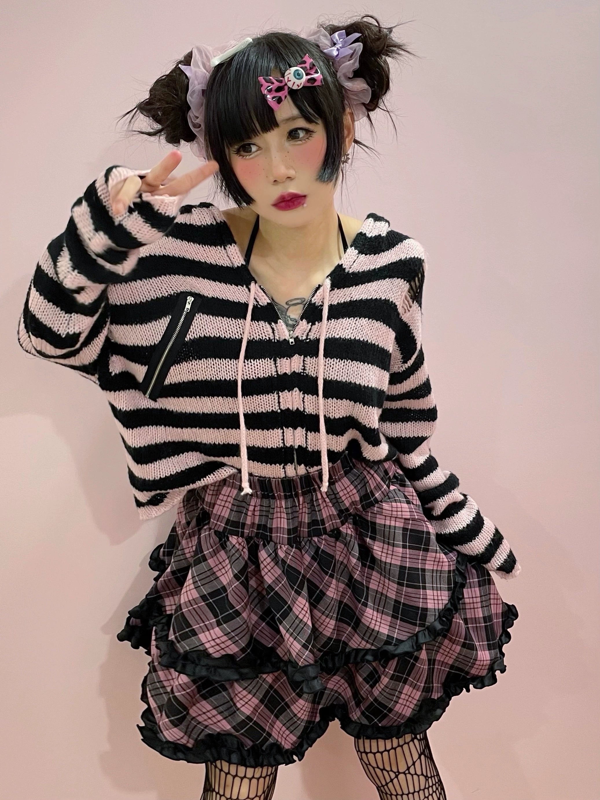 Jirai Kei plaid ruffle mini skirt worn with fishnet stockings, platform shoes, and goth alternative punk aesthetic styling