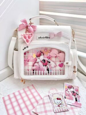 White kawaii jirai kei ita bag with clear display window and pink bow ornaments flat lay top view showing checkboard inner pocket and detachable crossbody strap
