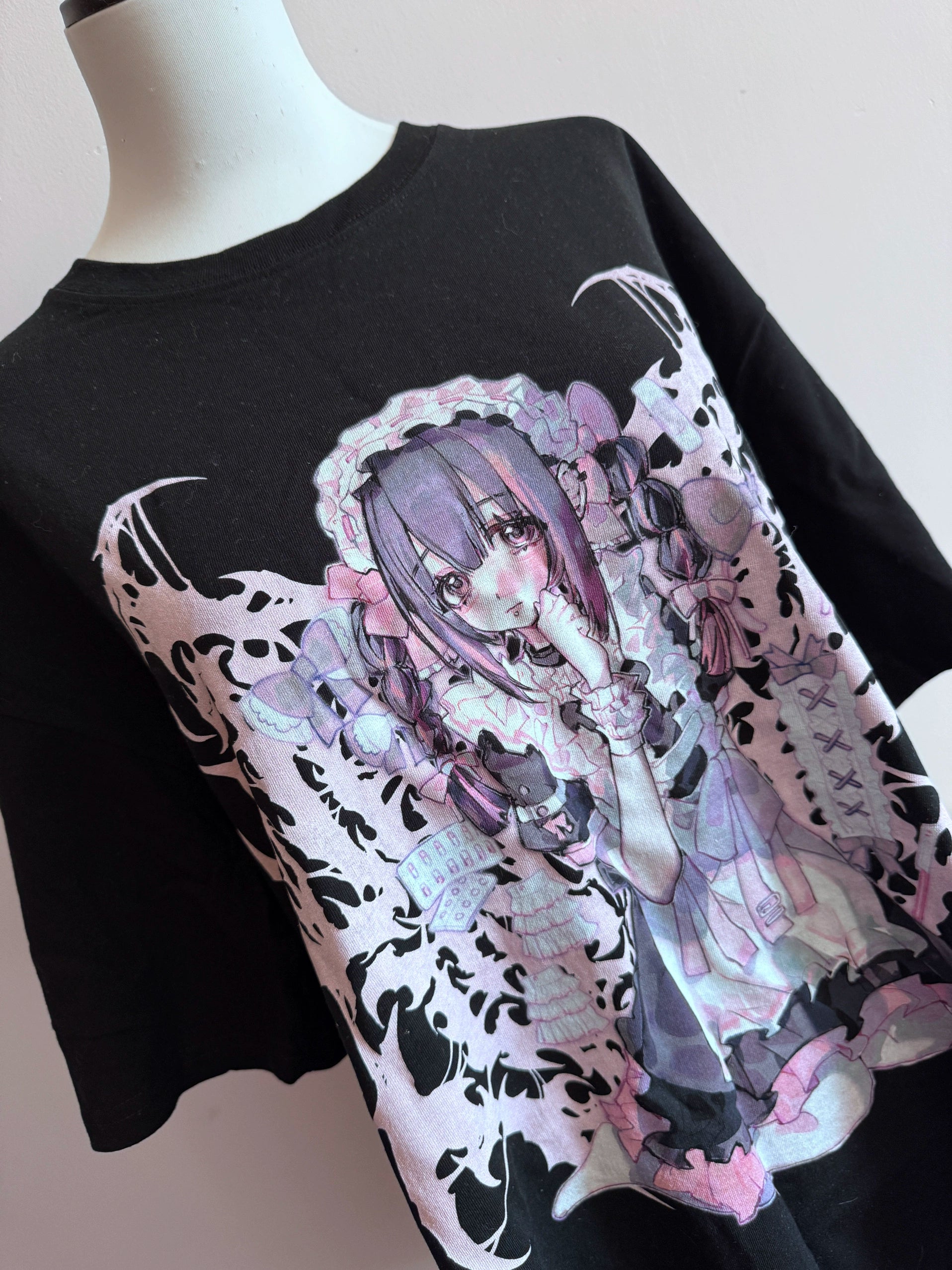 Black oversized Jirai Kei anime maid graphic t-shirt flat lay display on mannequin, showcasing detailed pink and purple anime girl print and relaxed fit silhouette