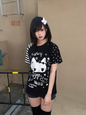 Black Jirai Kei cat print t-shirt kawaii anime style front full view outdoor stair area polka dot sleeves white cat and star prints female model with hair clip