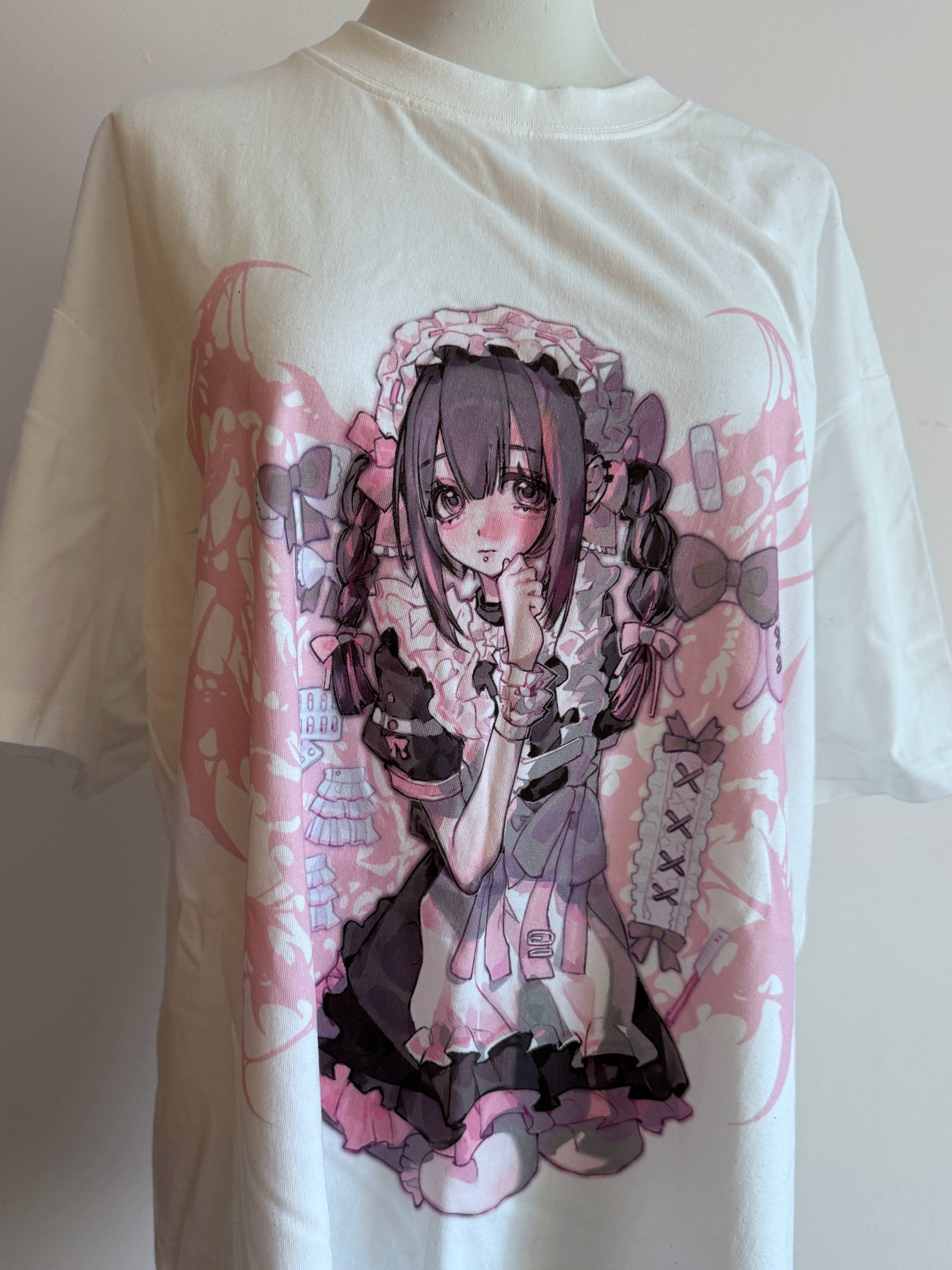White oversized Jirai Kei anime maid graphic cotton t-shirt displayed on mannequin, front hanging view showing pink and purple anime print design