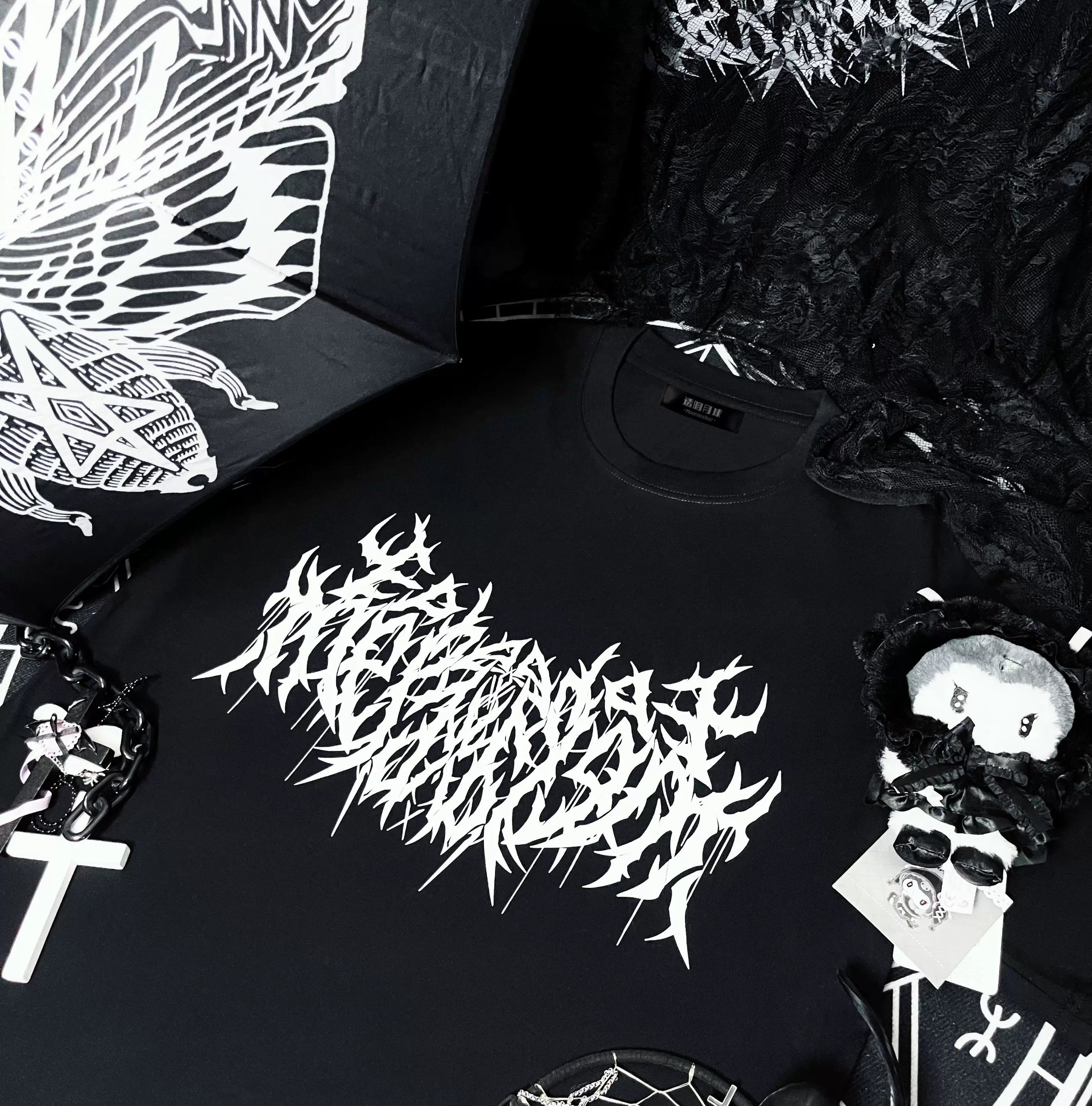 Black oversized gothic print cotton t-shirt jirai kei flat lay view with cross chain pendant and dark plush accessories