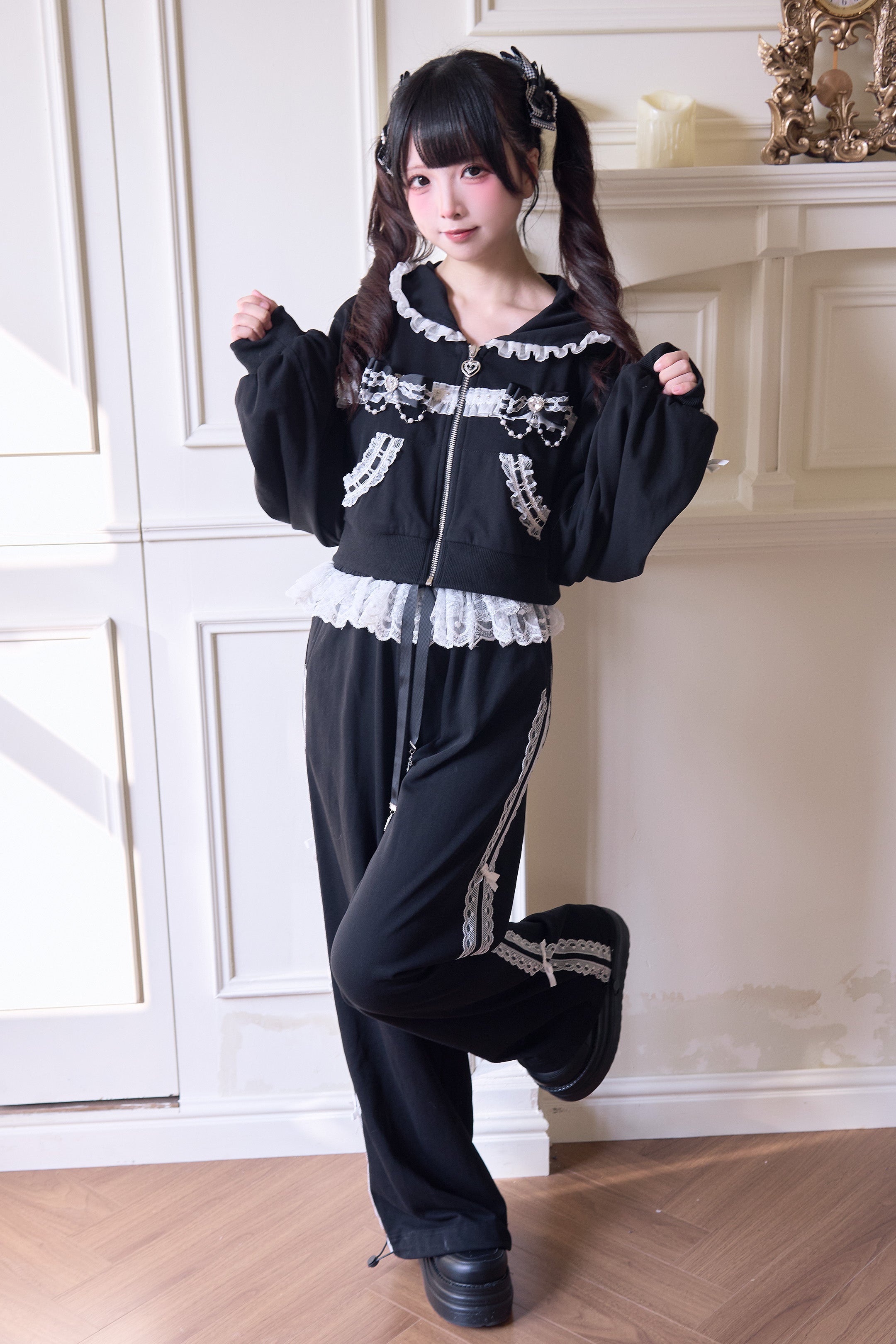 Black Jirai Kei wide-leg sport pants with lace side stripes three-quarter side view leg-raised pose on model