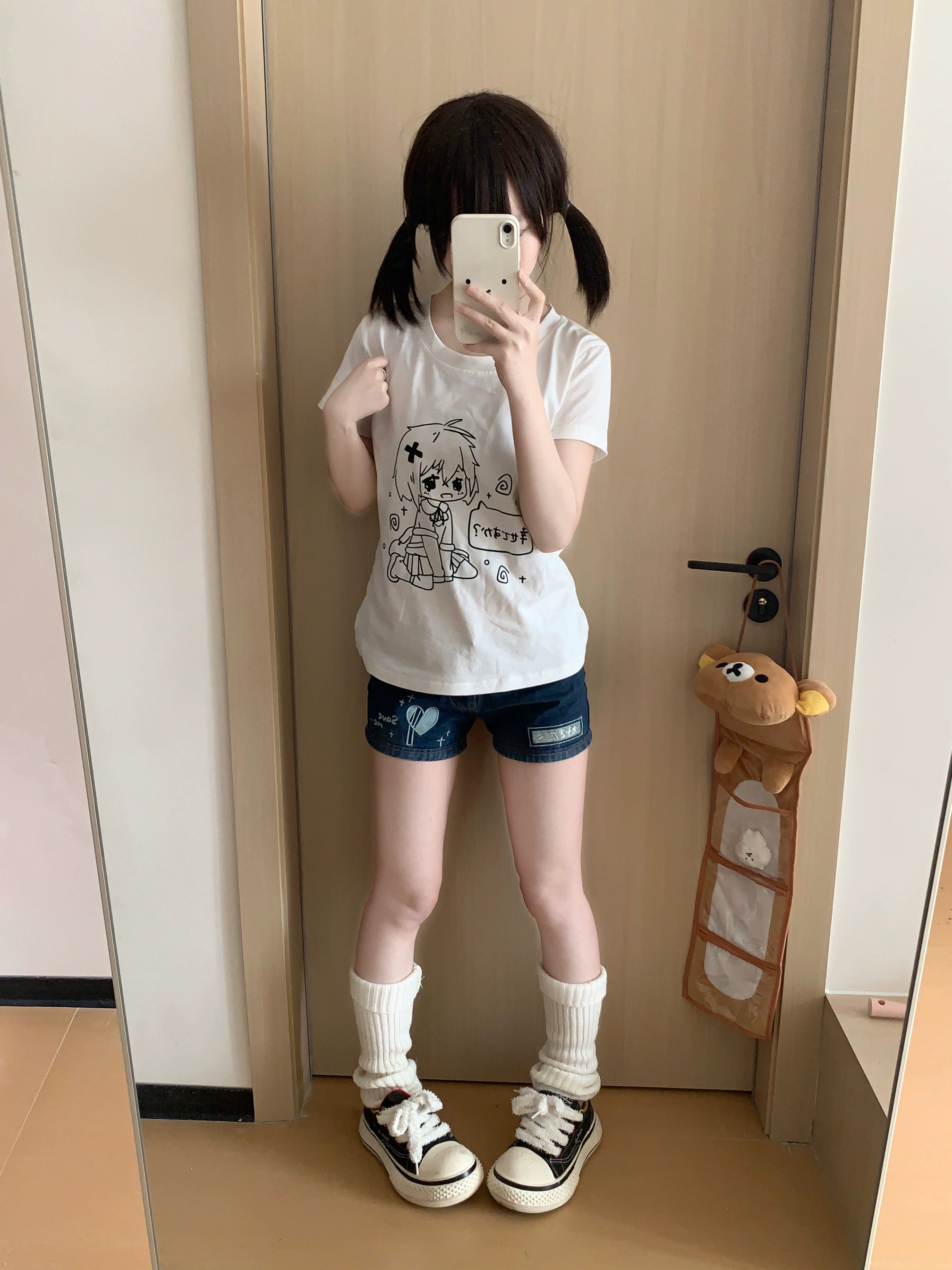 Kawaii anime graphic white t-shirt full-length on model with hand on chest posing in home doorway mirror reflection