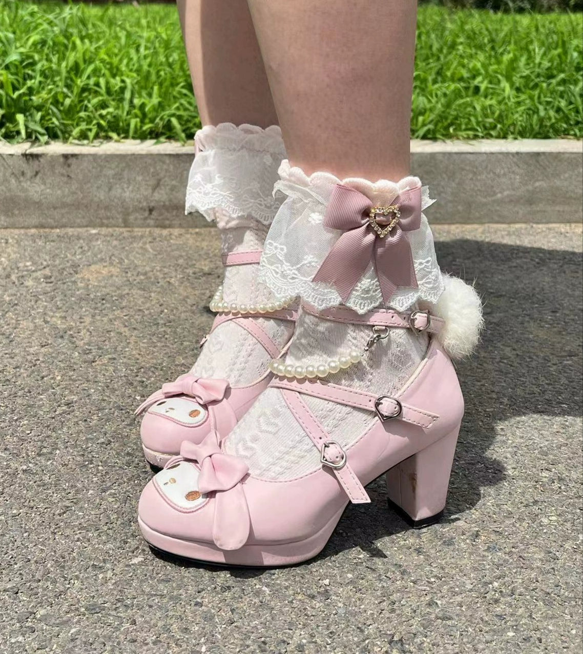White and pink Jirai Kei lace socks worn on feet with Mary Jane pink heels outdoor styling with ruffled lace cuff