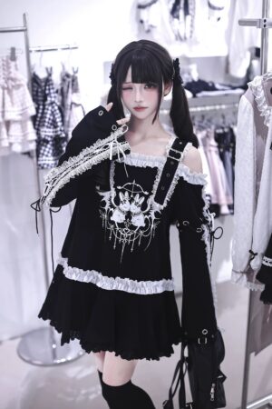 Black punk bunny jirai kei off-shoulder t-shirt dress with white lace trim and chain print, front close-up view on model with black twin tails