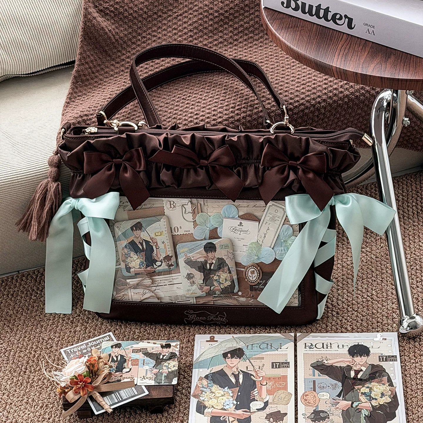 Dark brown Jirai Kei itabag flat lay front view mixed ribbon trims tassel charm clear comic photo display dual top handles home interior