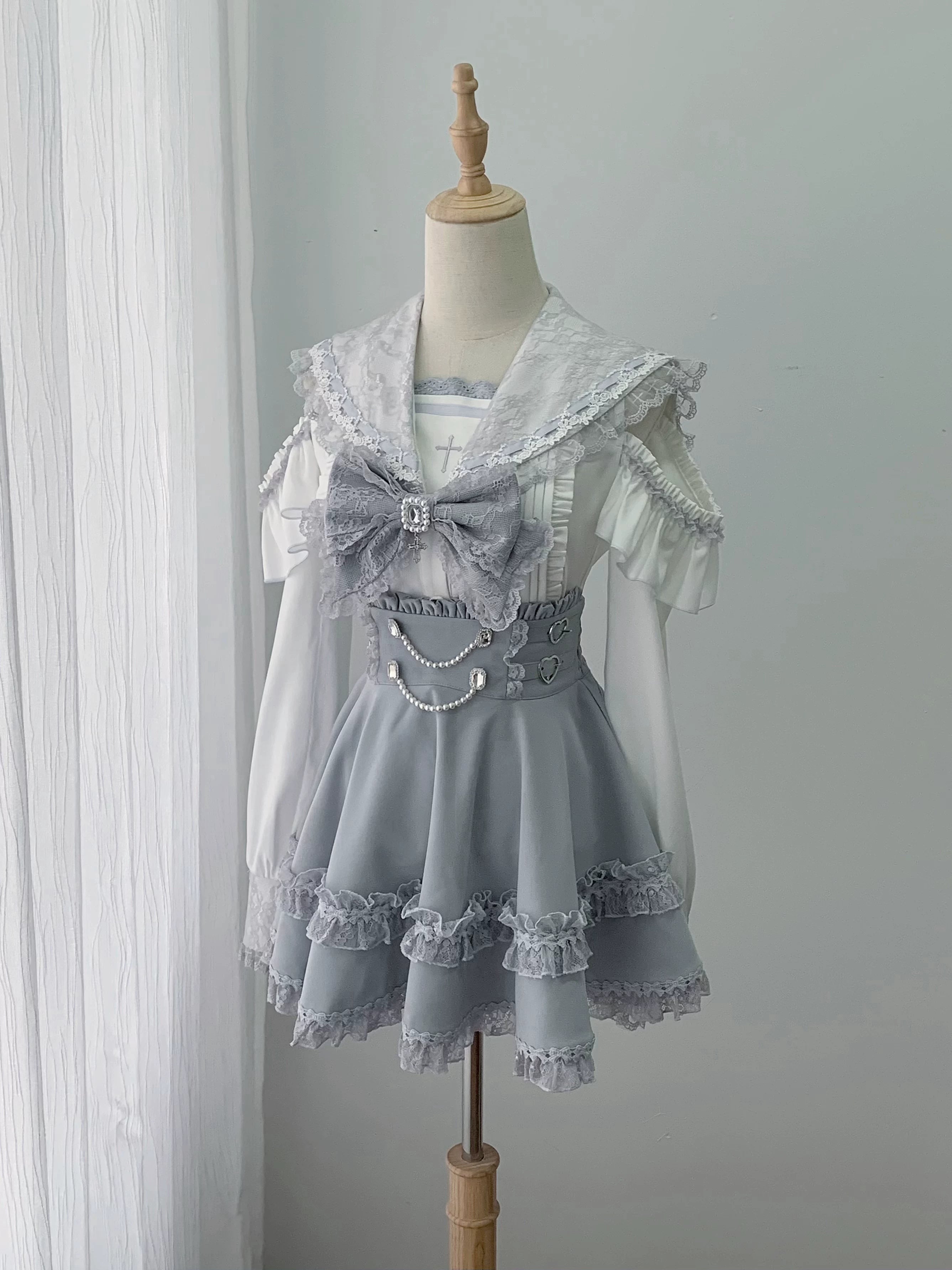 Flat lay display of complete ryousangata two-piece jirai kei outfit featuring lace sailor collar blouse with detachable bow and high-waist skirt with pearl chain waist decoration