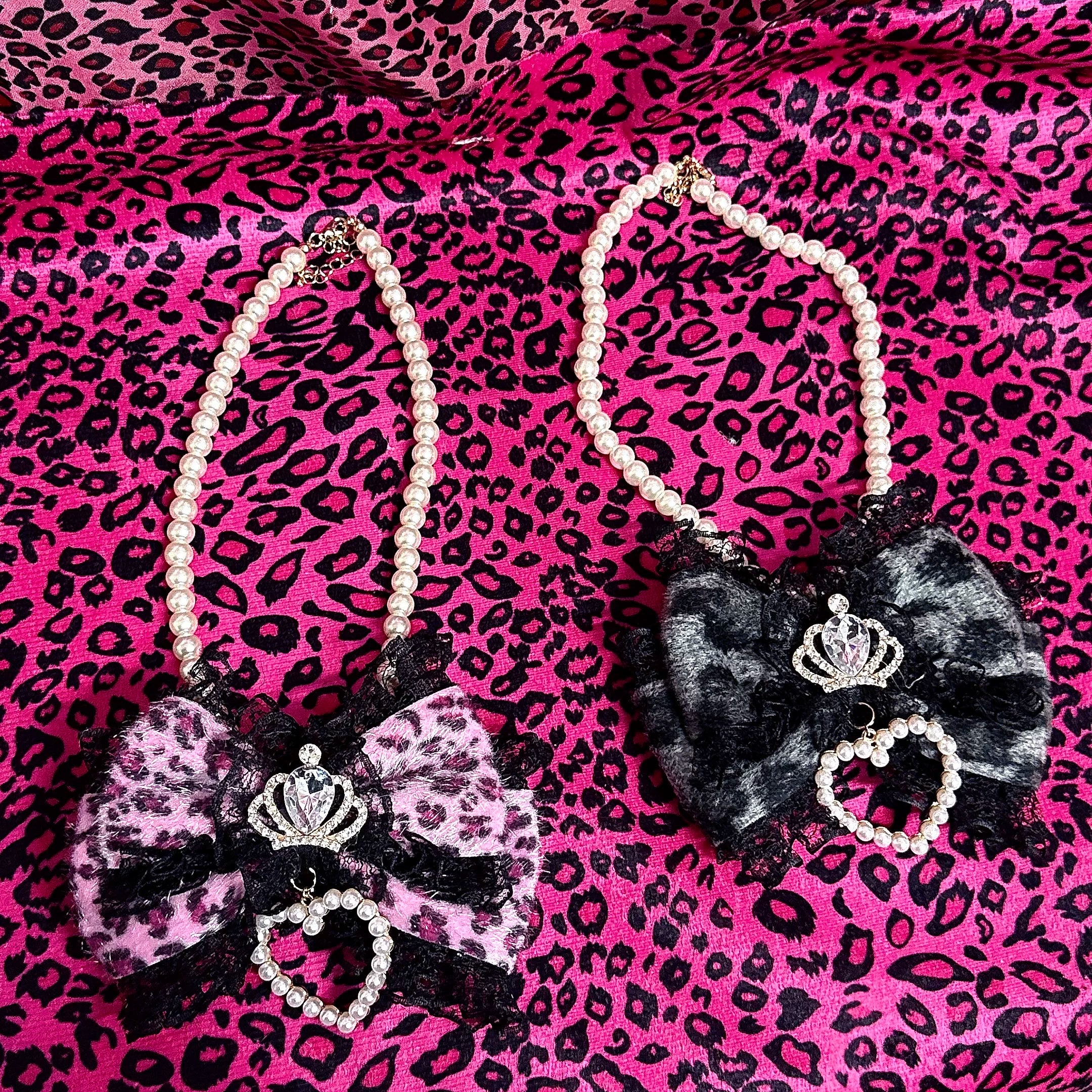 Two leopard pearl bow chokers in pink and grey with matching crown rhinestone and heart pearl details flat lay