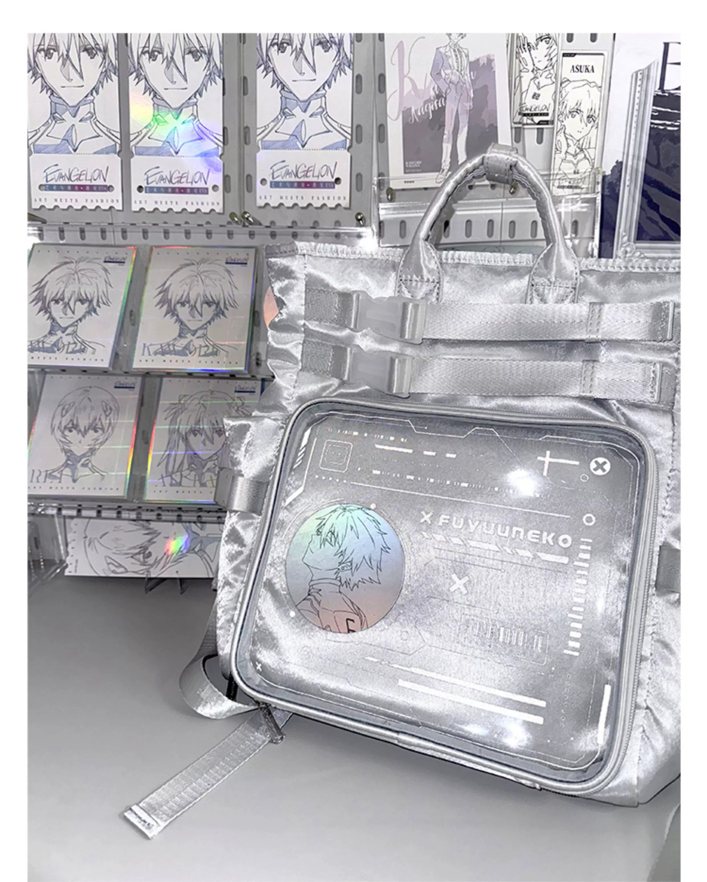 Silver cyberpunk Jirai Kei ita backpack front three-quarter view with clear anime badge window against anime merchandise display wall background