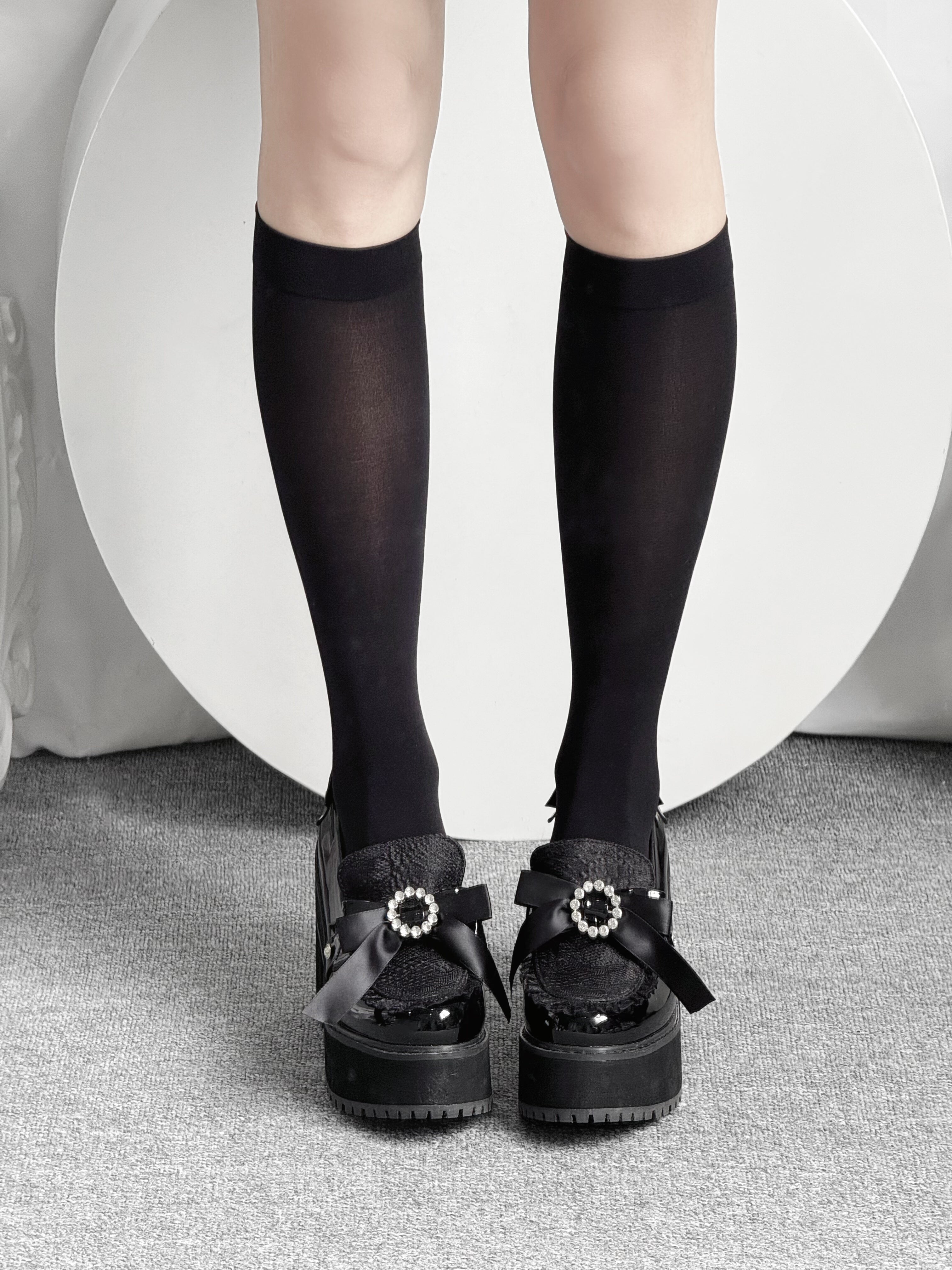 Black Jirai Kei knee-high socks front-facing view paired with black platform loafers studio backdrop
