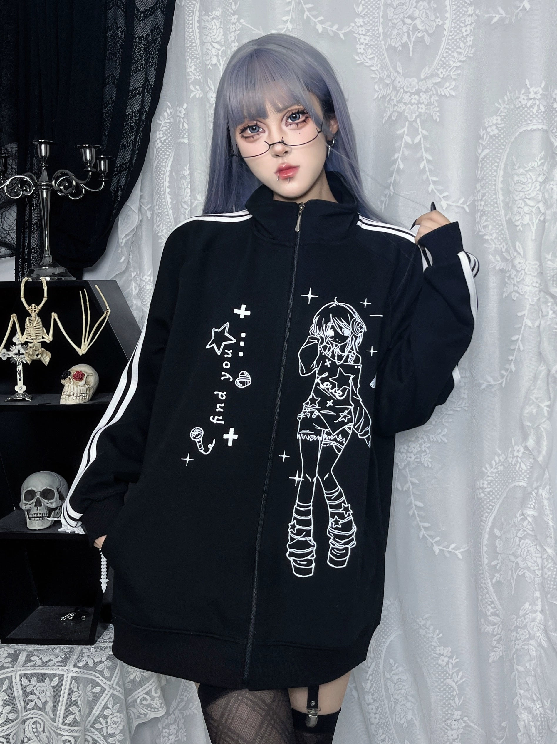 seated front view of black stand collar zip-up jacket with hip-length oversized fit and anime front print, gothic room setting