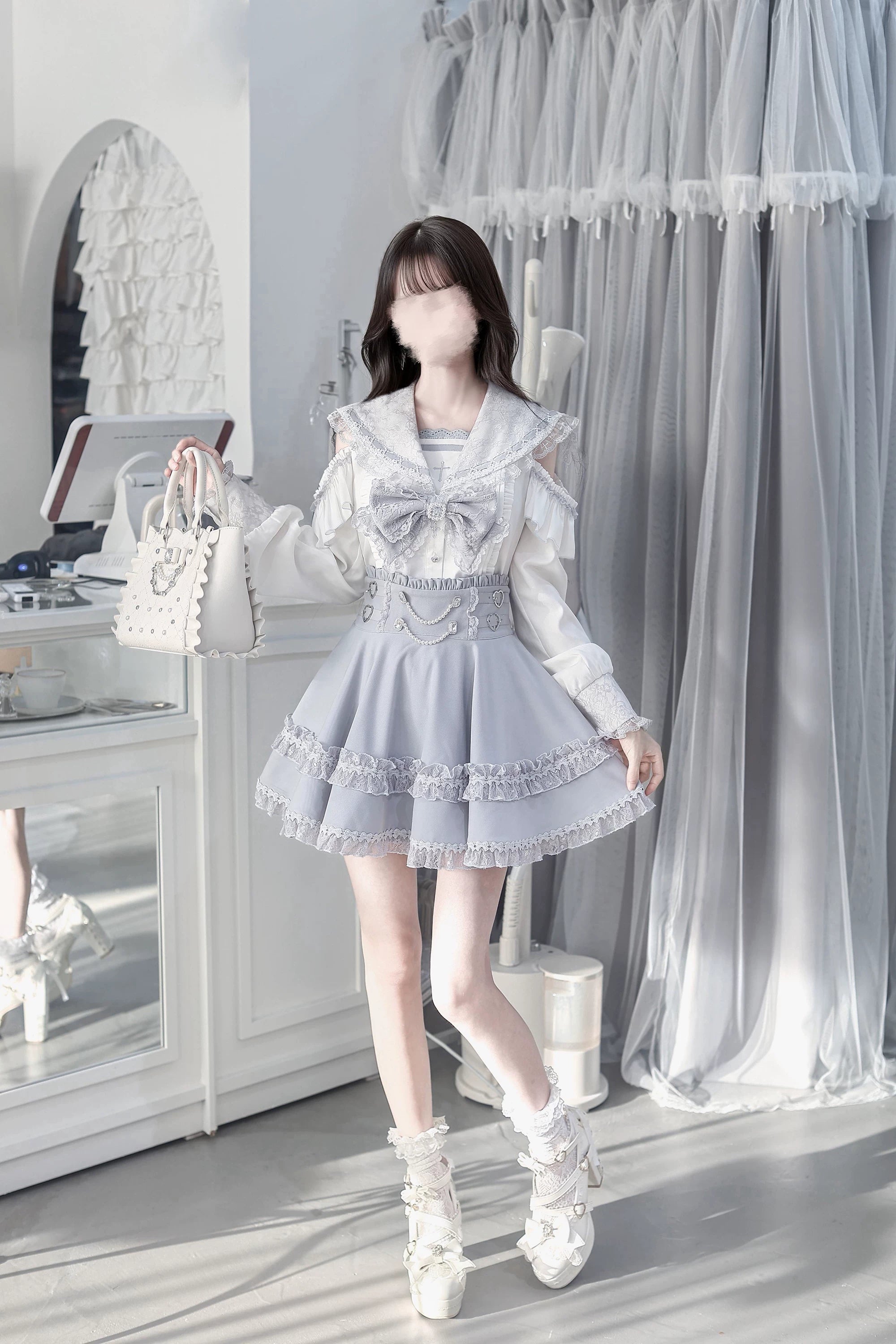 Right side three-quarter view of ryousangata sailor jirai kei outfit featuring long puff cold-shoulder sleeves heart waist embellishments and model holding structured handbag