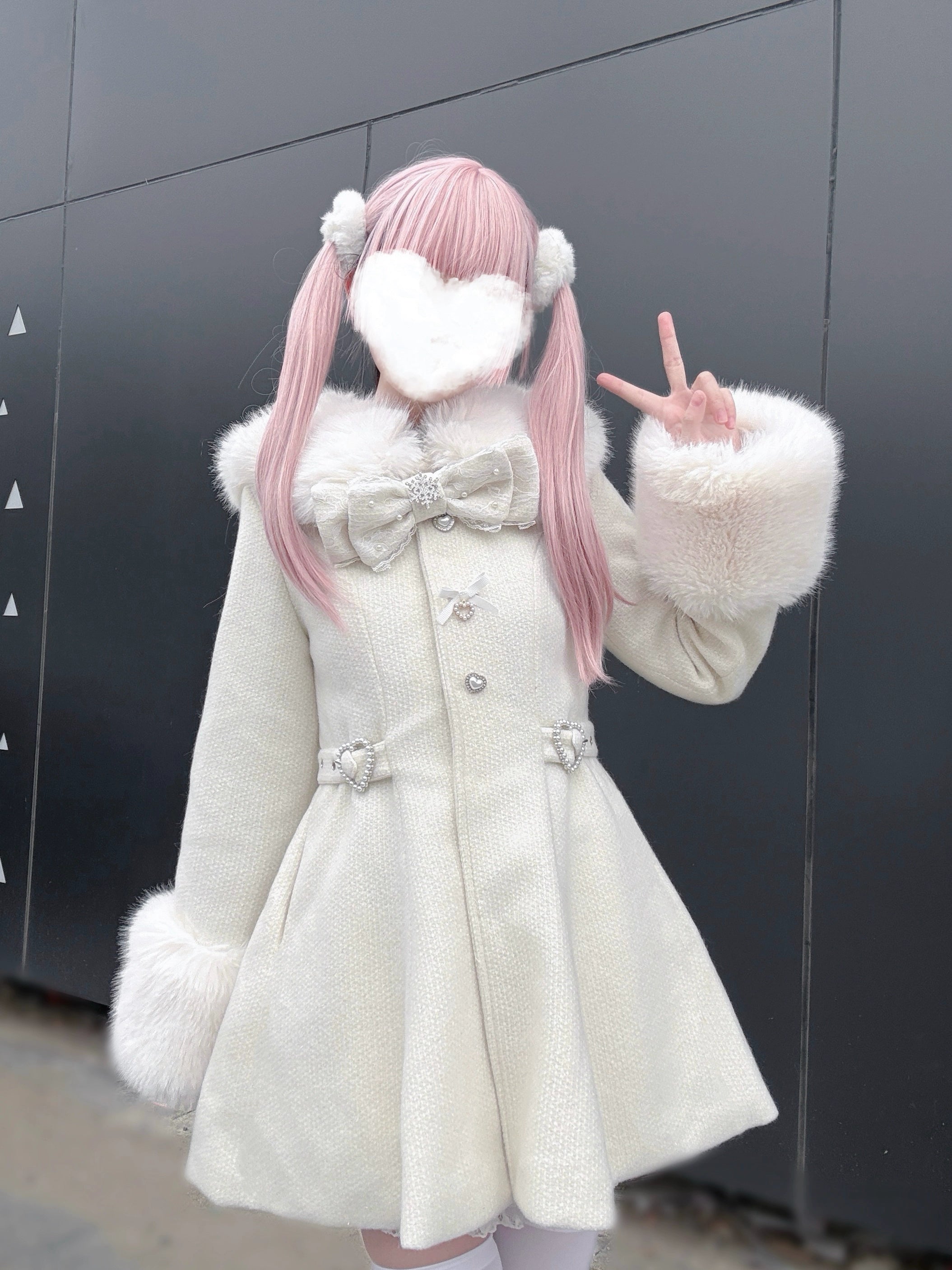 Beige Ryousangata tweed coat model making peace sign gesture showing sleeve faux fur and bow detail front three-quarter angle dark gray wall