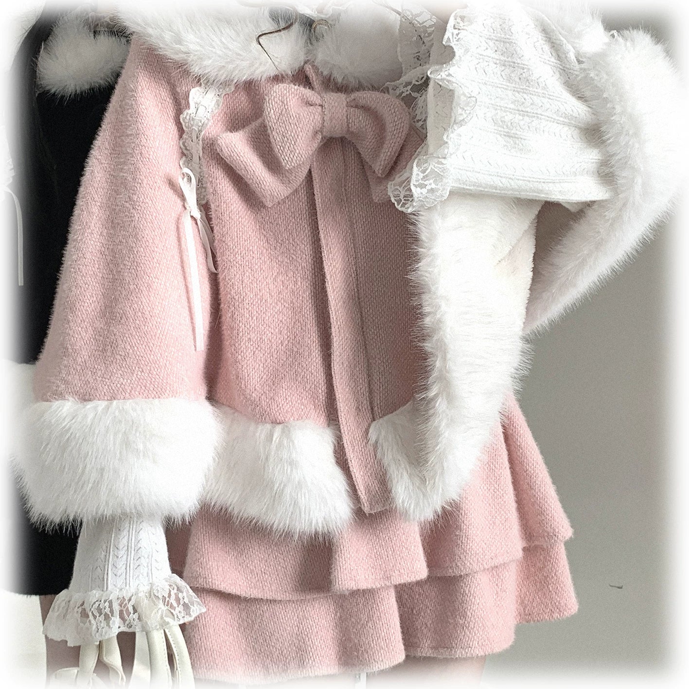 Side profile of pink Jirai Kei bunny ear winter cape with detachable fuzzy shawl bow decor and delicate ruffle cuffs on model