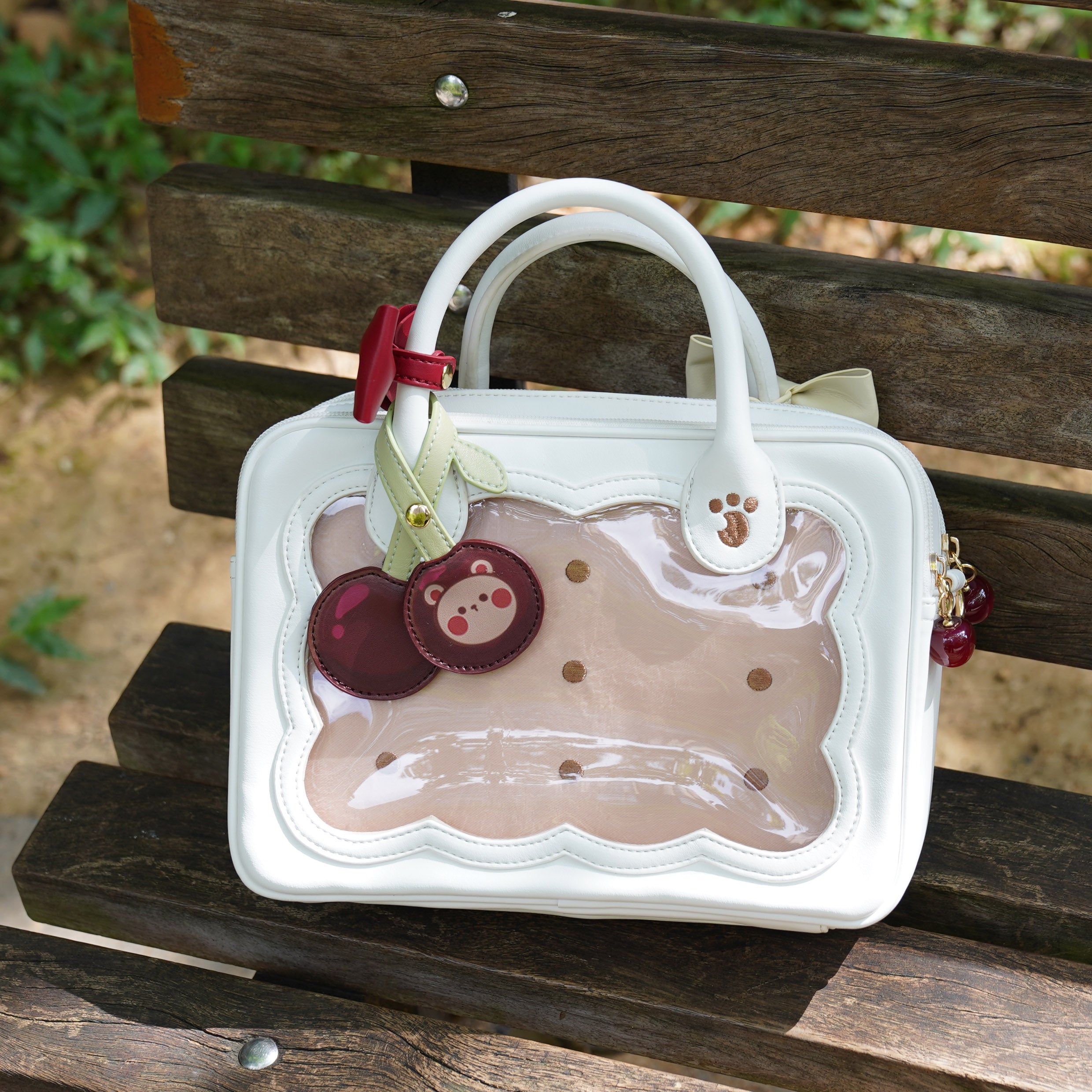 Bright white cherry bear cookie Jirai Kei bag with red handle bow and decorative bear charms close-up detail shot