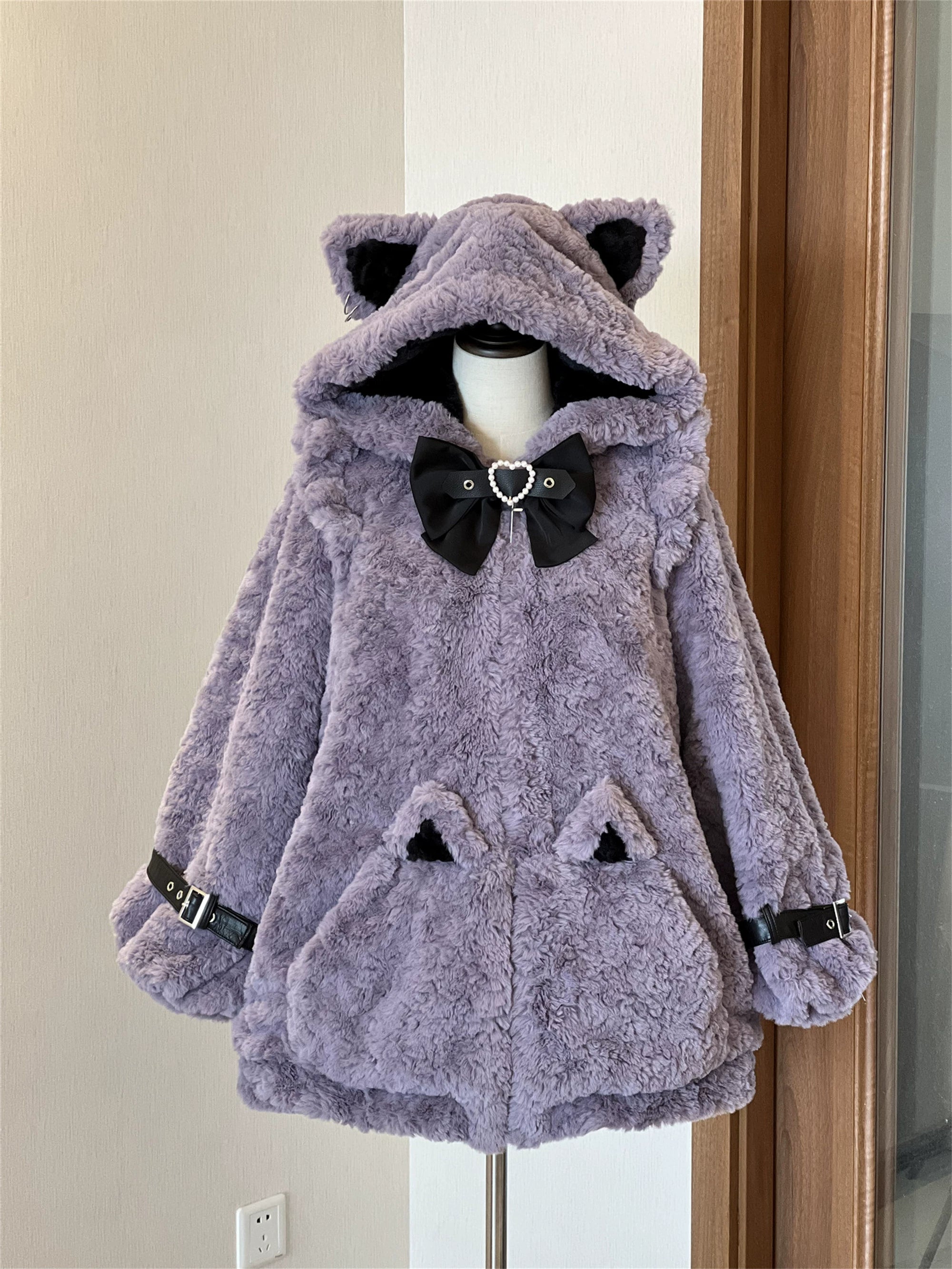 Purple plush Jirai Kei cat ear fleece coat with black heart bow decoration, centered front zipper closure, and cat ear pocket patches, mannequin display