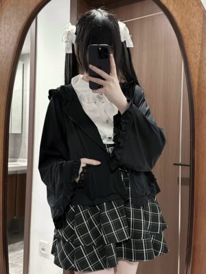 Black Jirai Kei cat ear hoodie jacket with ruffled trim worn by model with twin tails and white hair bows, styled with frilly white blouse and plaid mini skirt, front mirror selfie