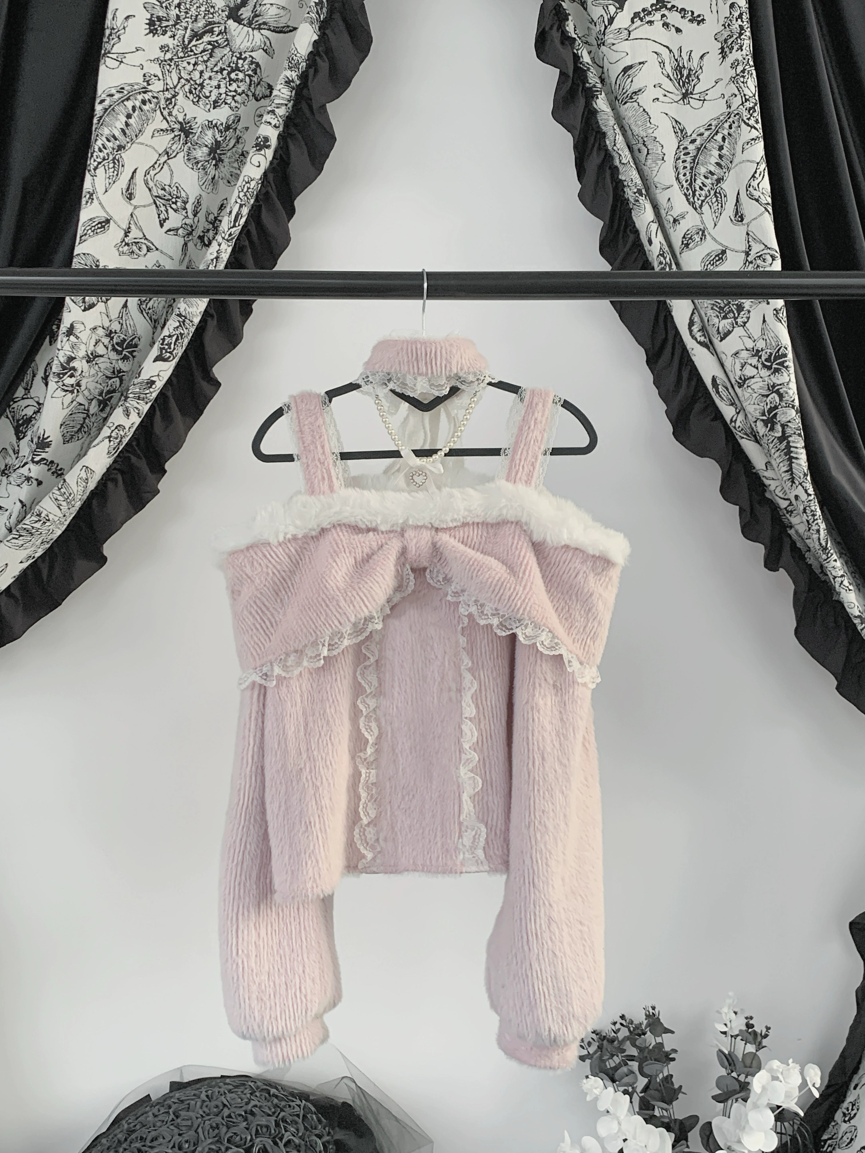 Pink off-shoulder plush fleece top with front bow and ruffle trim displayed on mannequin, showing fuzzy plush fabric construction