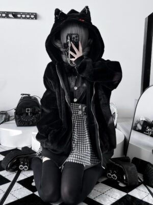 Black Jirai Kei cat ear plush winter coat with cross charm hood, oversized fit shown on model in mirror selfie wearing houndstooth skirt, featuring red embroidery details and decorative pins