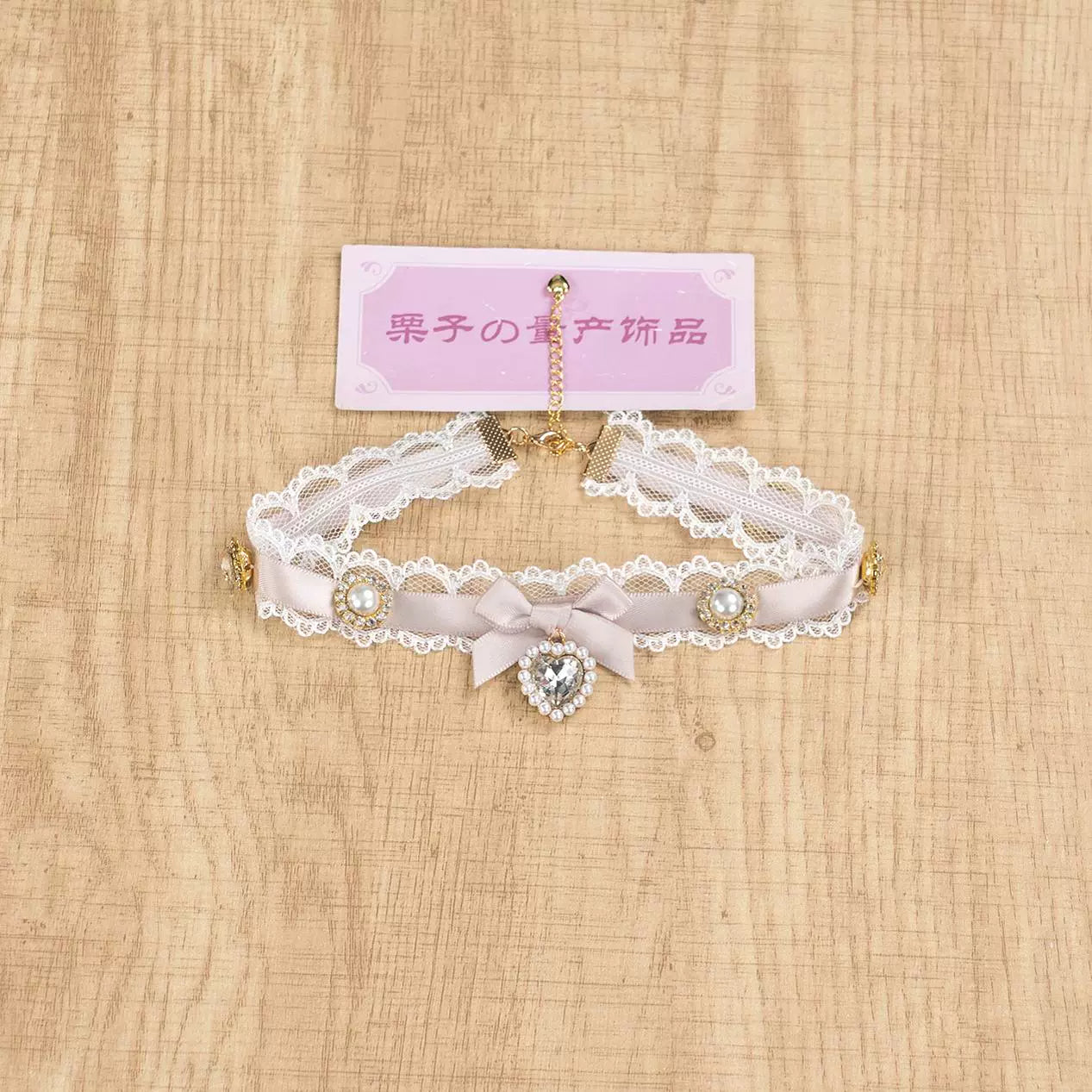 White and pink Jirai Kei choker necklace with bow-shaped center and heart rhinestone pendant on brand tag display
