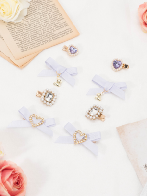 Light purple lavender bow hair clips with rhinestone heart and round pendant charms in Jirai Kei style aesthetic vintage book background