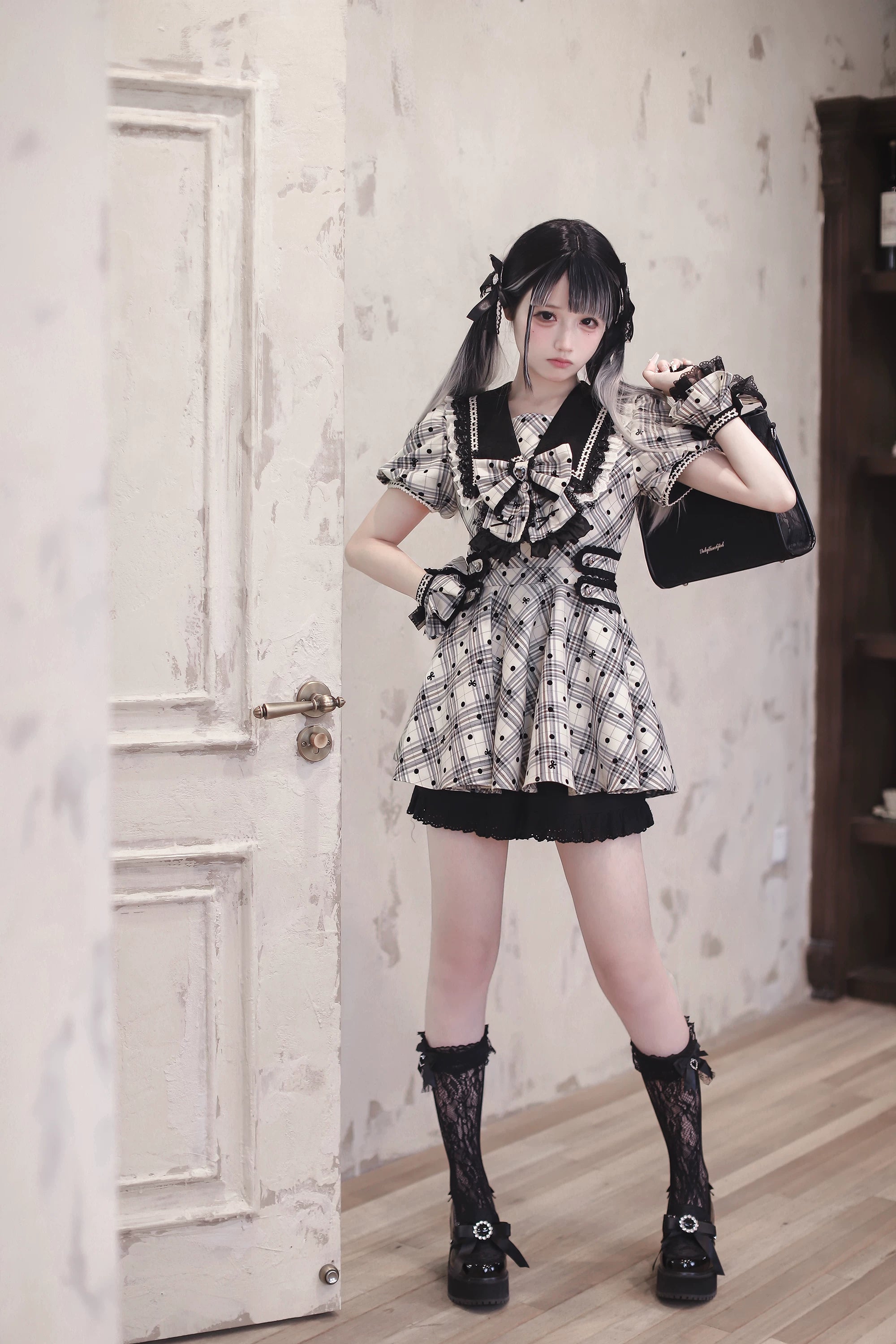 Close-up flat lay showing yarn-dyed plaid fabric with flocked polka dots and tiny bow accents on Jirai Kei dress demonstrating premium flocking process instead of printing
