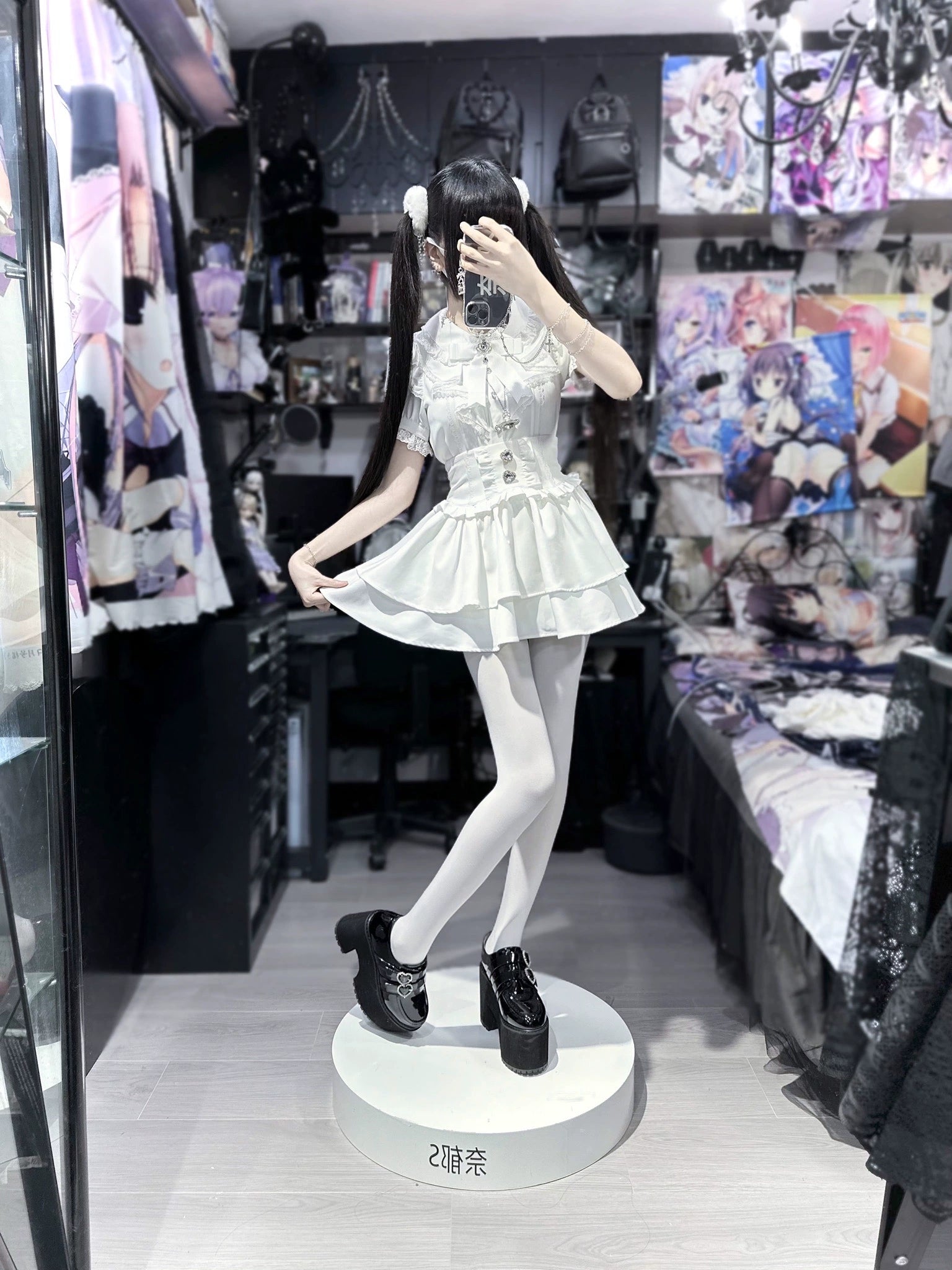 White jirai kei tiered mini dress set on mannequin full-length view, fitted bodice with ruffled skirt, black platform shoes, anime store display