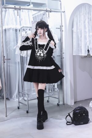 Full-body mirror shot of punk bunny jirai kei dress with ruffled hem and long sleeves on black twin-tailed model in fitting area