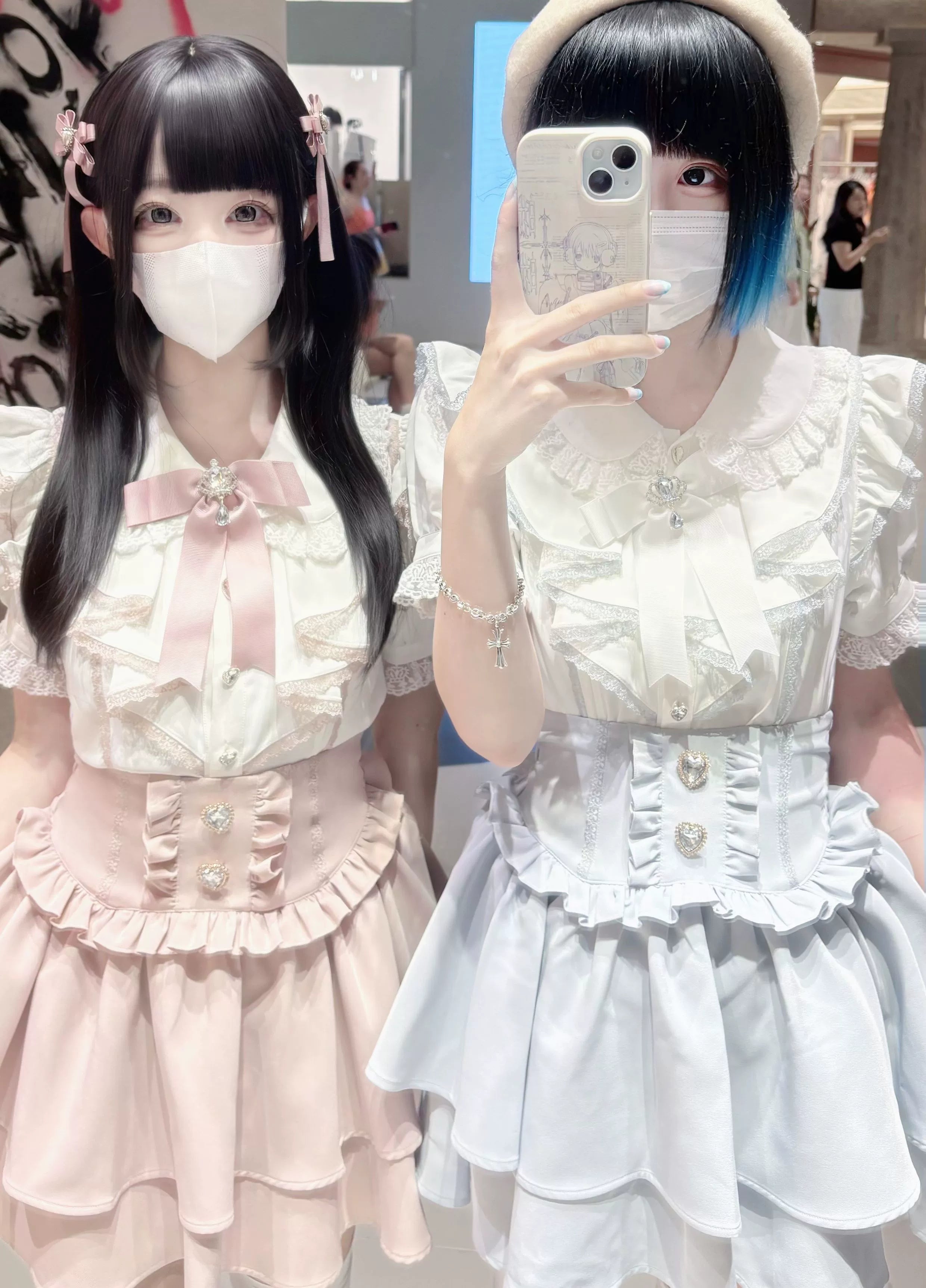 Jirai kei blouse and tiered skirt sets featuring heart-shaped decorative buttons, pink and white colorway options, close-up half-body mirror selfie