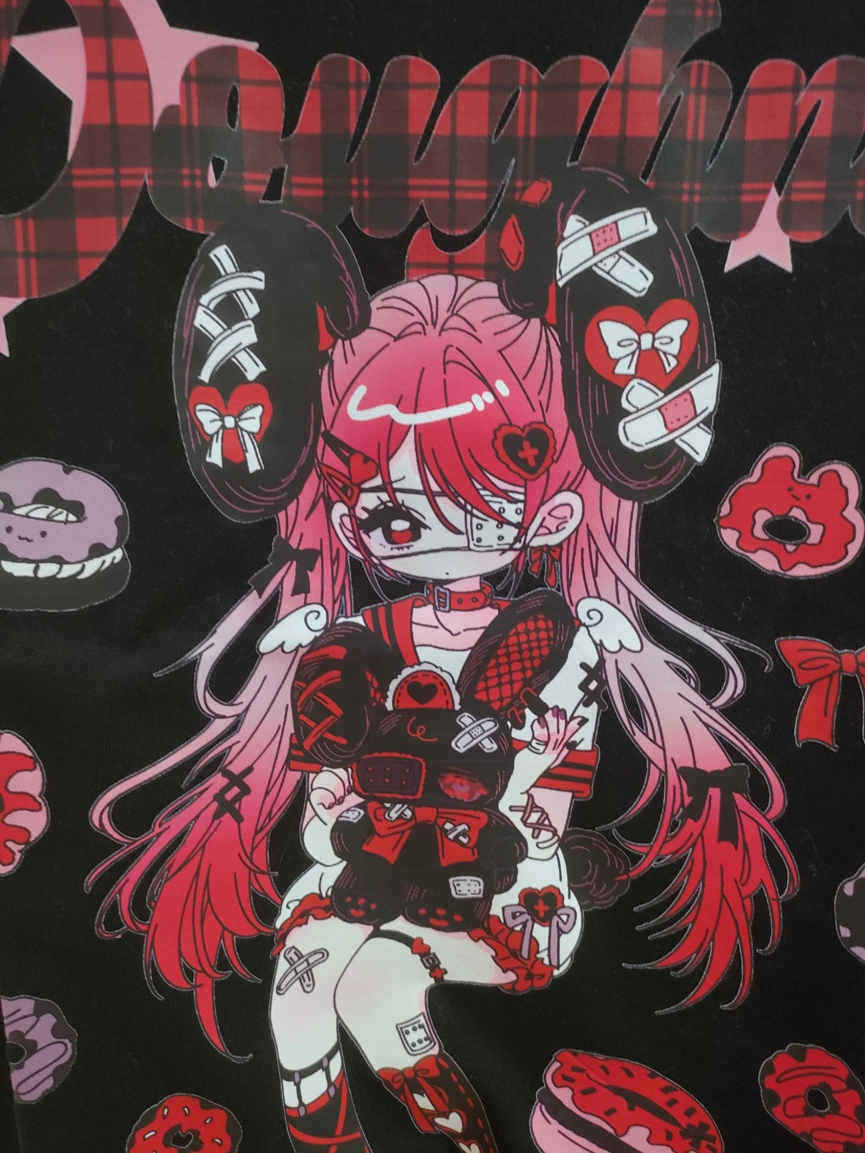 Flat lay front view of red and black Jirai Kei anime T-shirt print design showcasing red-pink anime girl with band-aids, heart bow and donut pattern decorations