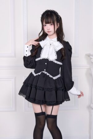 Black and white Jirai Kei long-sleeved dress with white lace trim and removable bow collar, front three-quarter view on female model wearing platform boots
