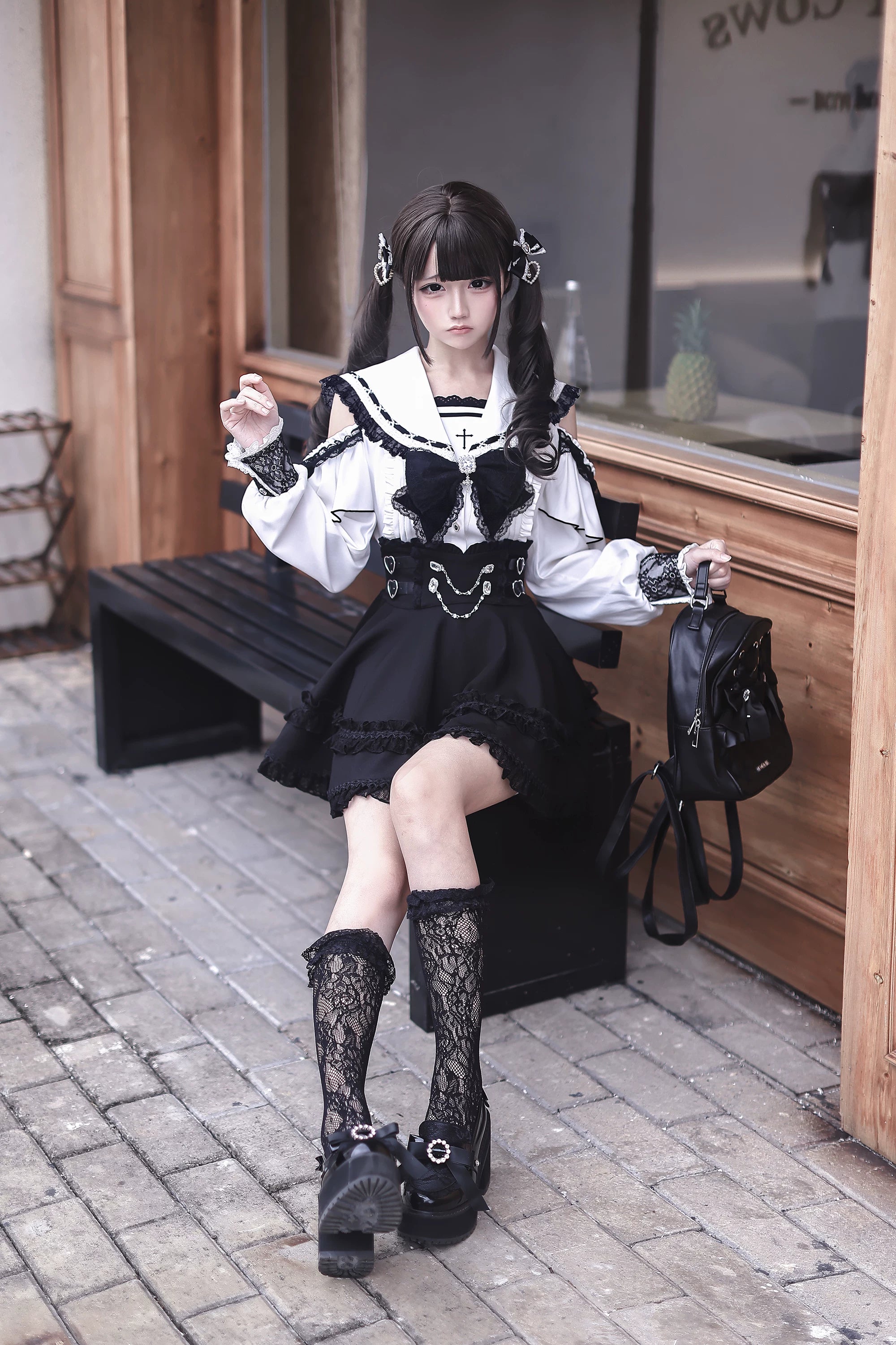 Jirai Kei sailor collar outfit three-quarter sitting view with model in outdoor street scene, lace socks and black backpack