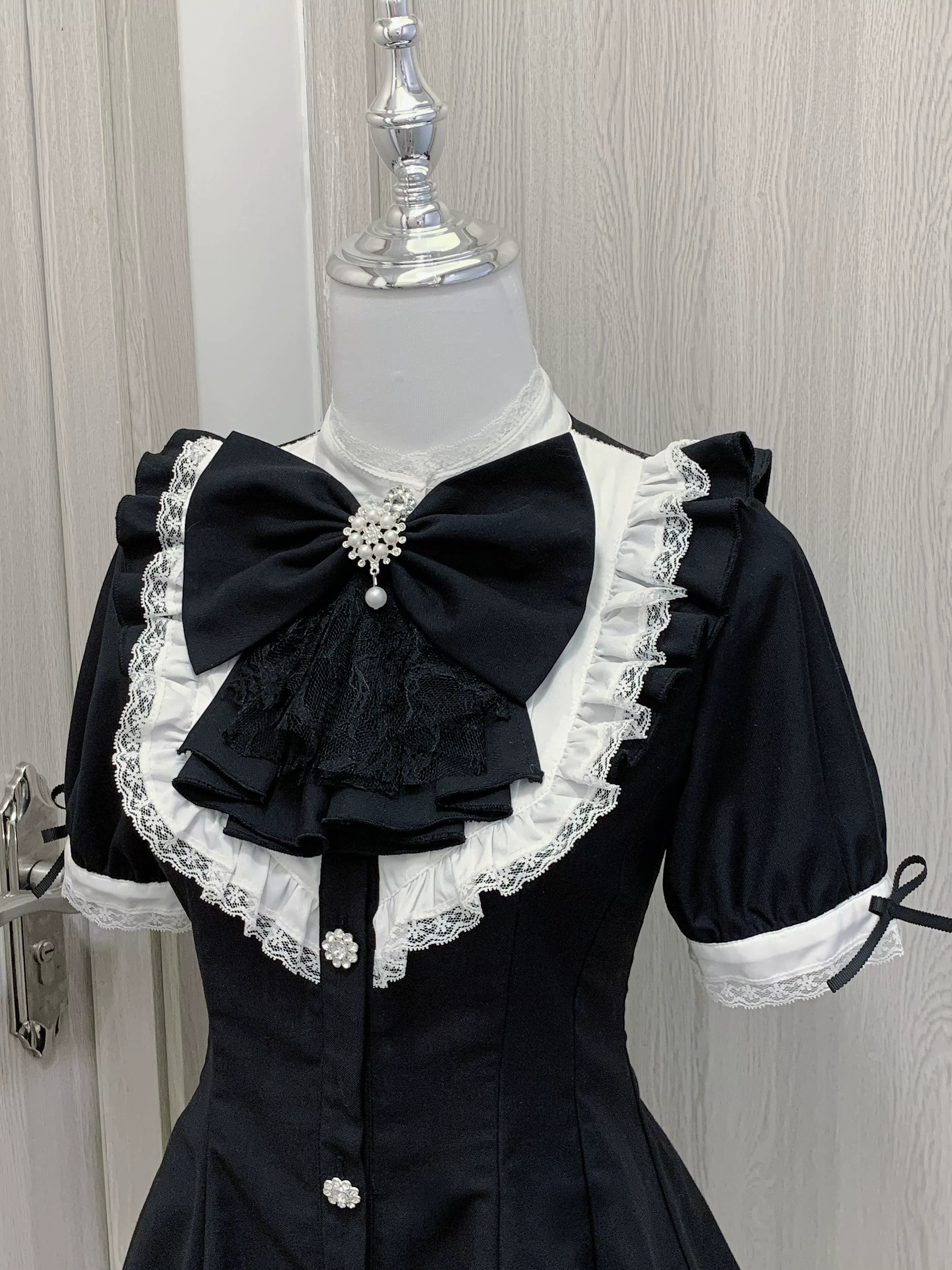 Close-up detail of Jirai Kei dress front showing intricate lace ruffled collar, decorative brooch accent, and button-down closure system