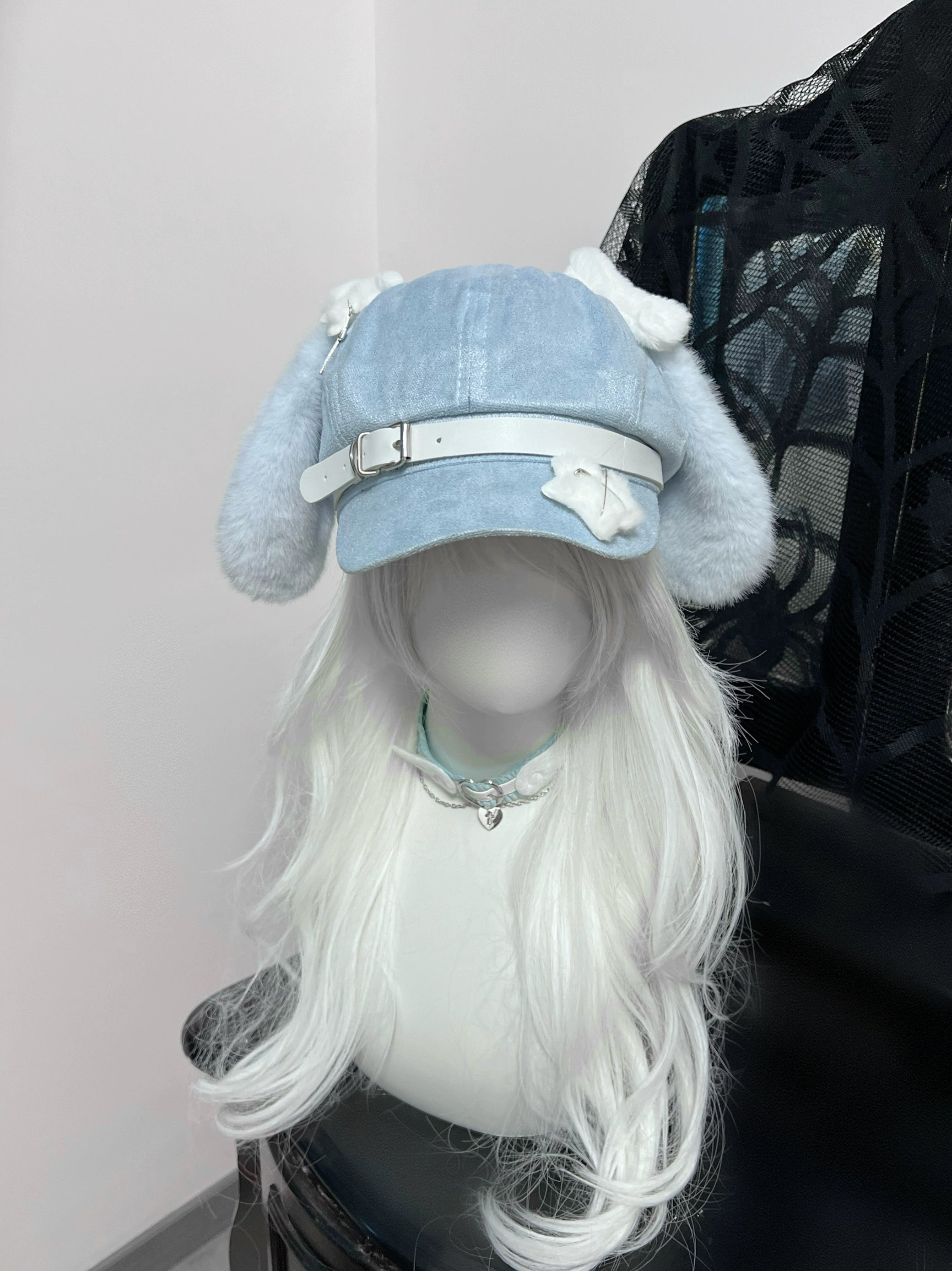 Side view display of blue puppy ear beret on mannequin showing bone-shaped ornament charm on white adjustable belt strap