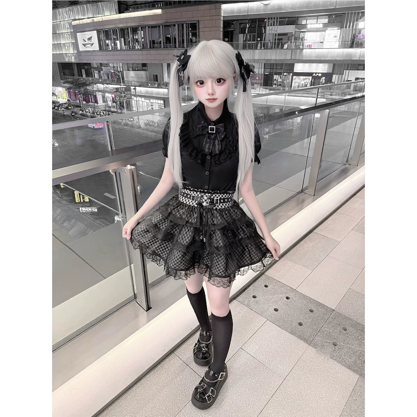 Jirai Kei black blouse plaid skirt tulle overlay ensemble front three-quarter view outdoor shopping mall model wearing complete outfit with layered skirt details