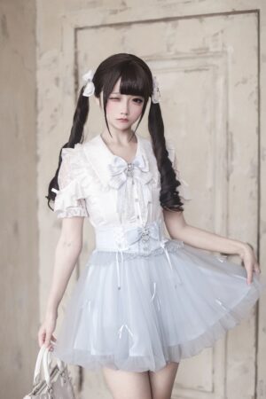 Front eye-level view of light blue ryousangata high-waist tulle bubble hem skirt with rhinestone bow, paired with white ruffle blouse in vintage wooden door setting - jirai kei lolita aesthetic