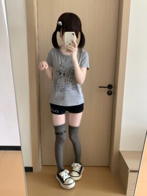 Full-length mirror selfie of heather gray yami kawaii t-shirt with anime sick girl IV drip print, worn by model with twin tails, showcasing slim-fit crew neck silhouette and front print design