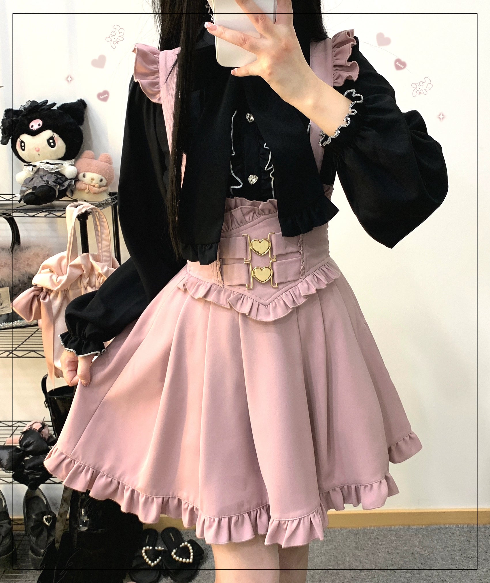 Pink ruffled hem Jirai Kei suspender skirt with heart-shaped metal buckle waistband worn in full-body mirror selfie with black ruffled blouse and heart-shaped handbag